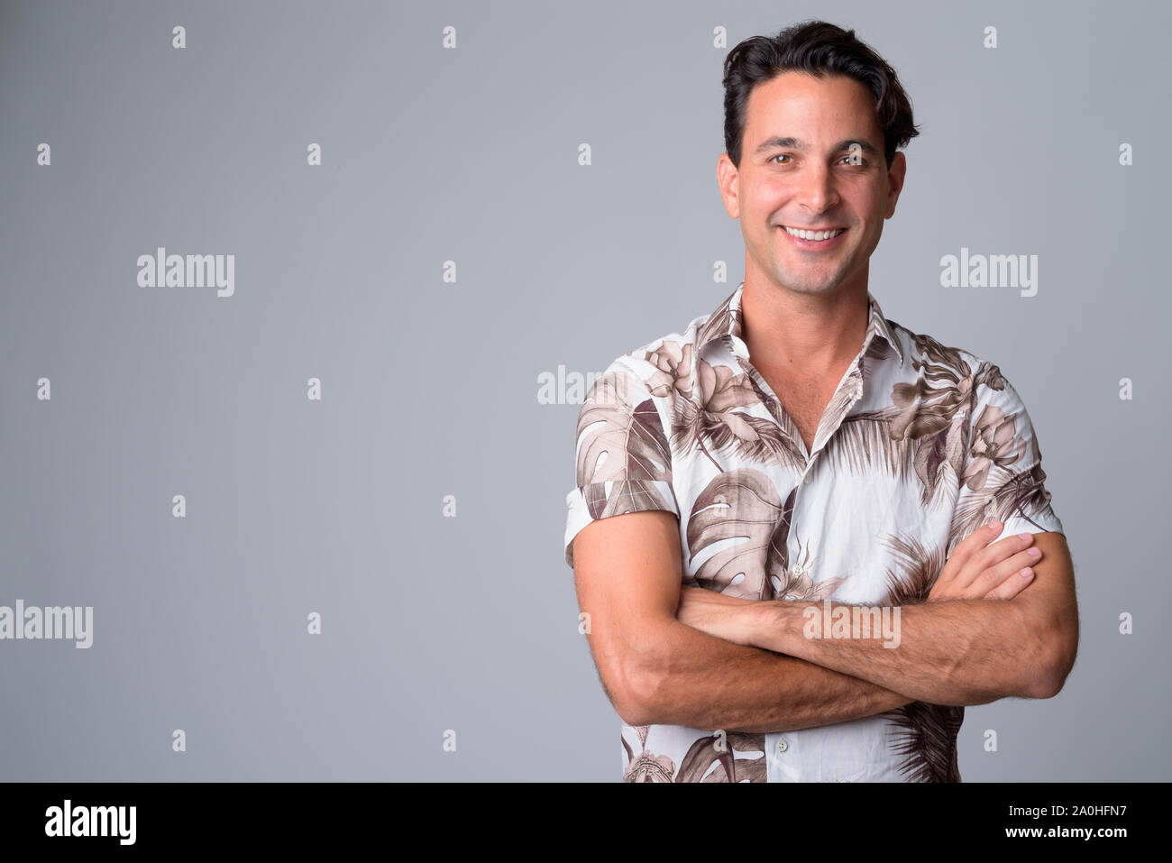 Portrait of happy handsome Hispanic tourist man smiling with arms ...