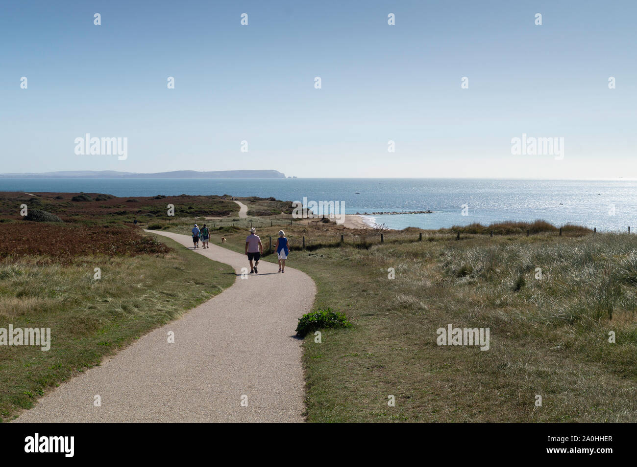 The Isle of Wight viewed from Hengistbury Head, with walkers in the foreground enjoying the late summer sunshine and stunning views. Stock Photo