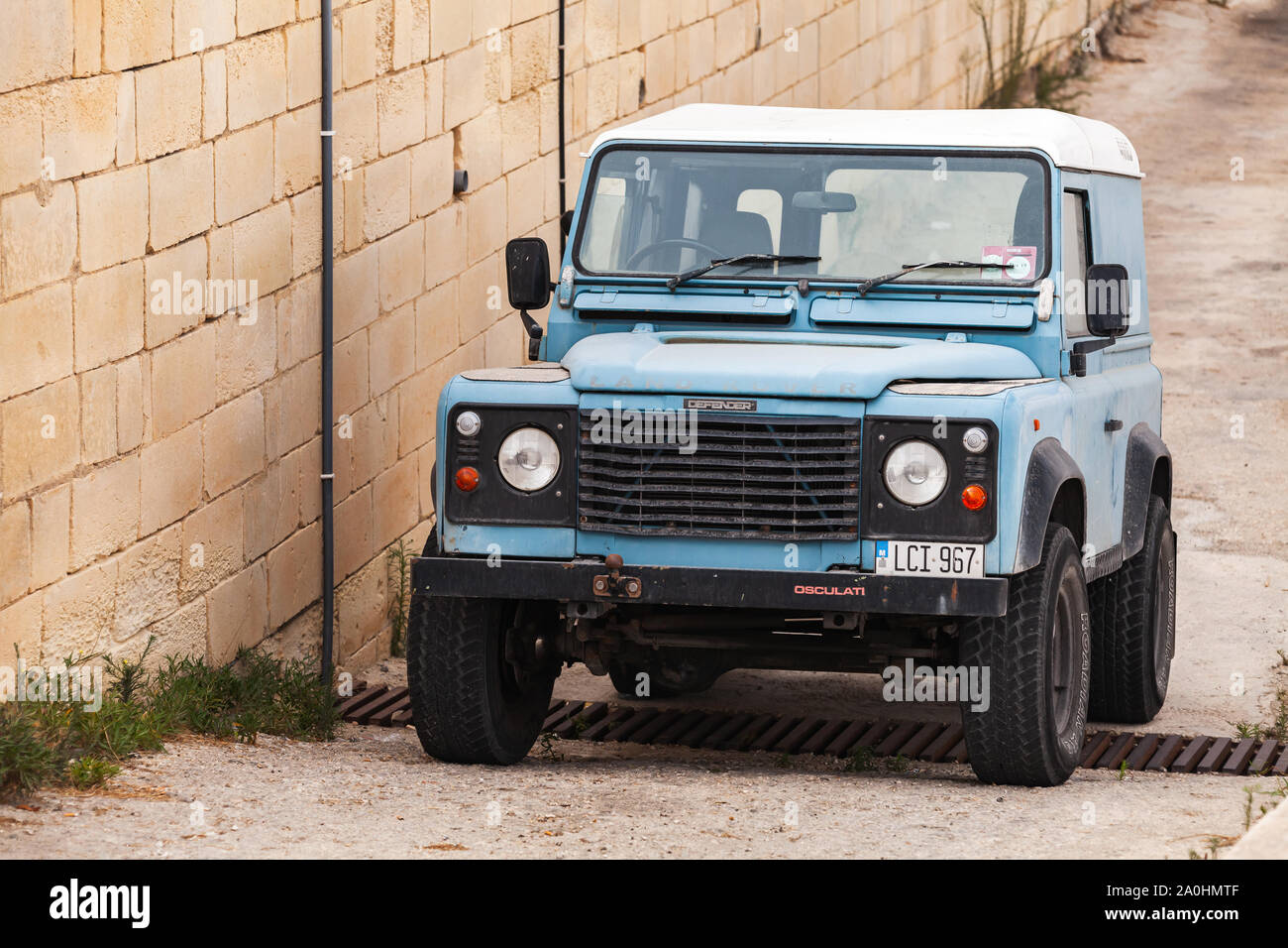 Cirkewwa, Malta - August 29, 2019: Blue Land Rover Defender stands on a roadside. This is a British four-wheel drive off-road vehicle developed in the Stock Photo