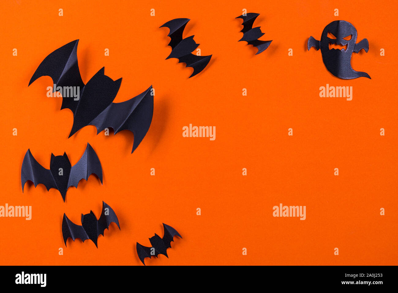 Halloween concept. Flock of black paper bats and ghost on orange paper ...