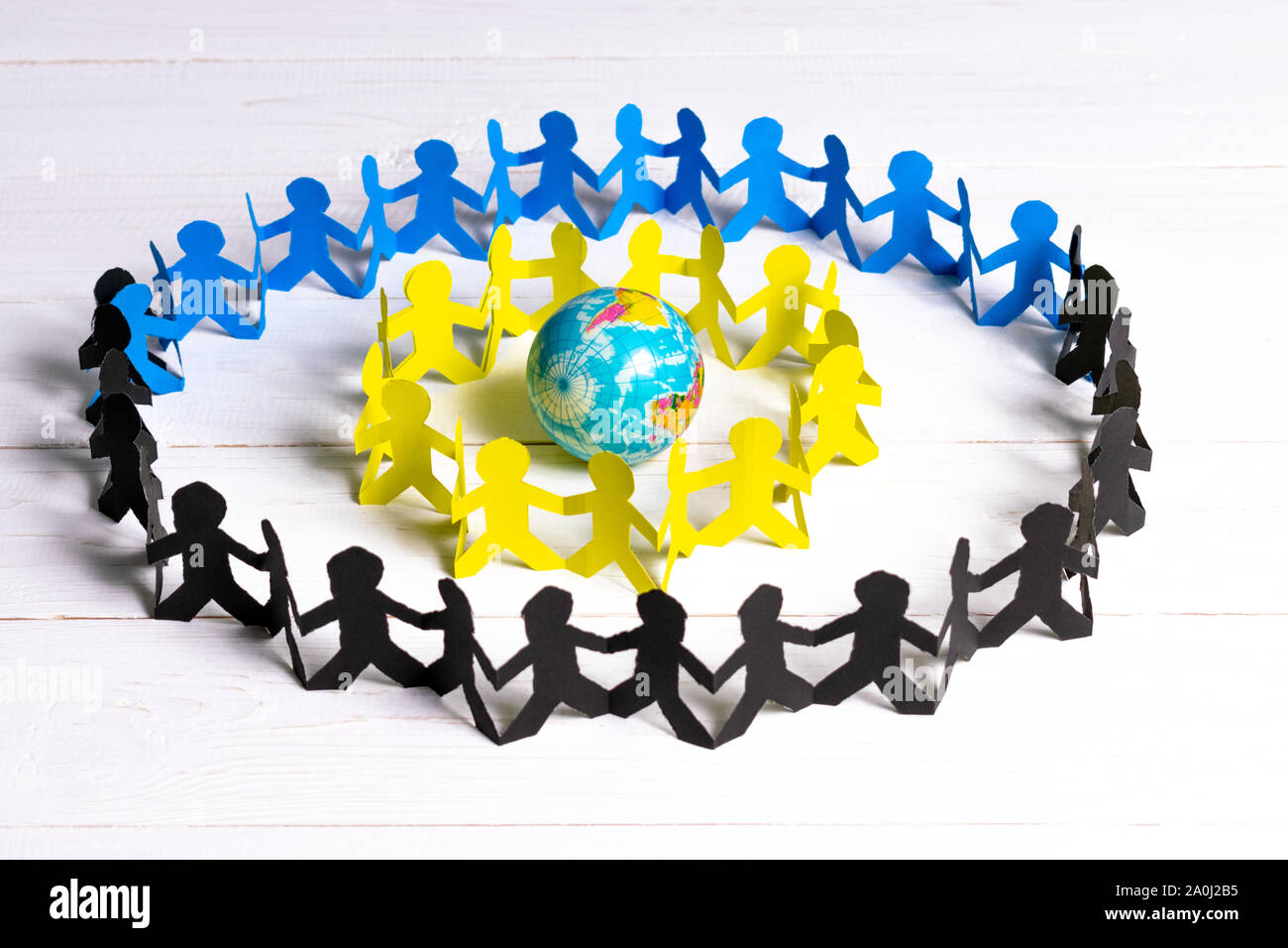 Circle of paper people holding hands around the globe made of paper cut . World Population Day. Stock Photo