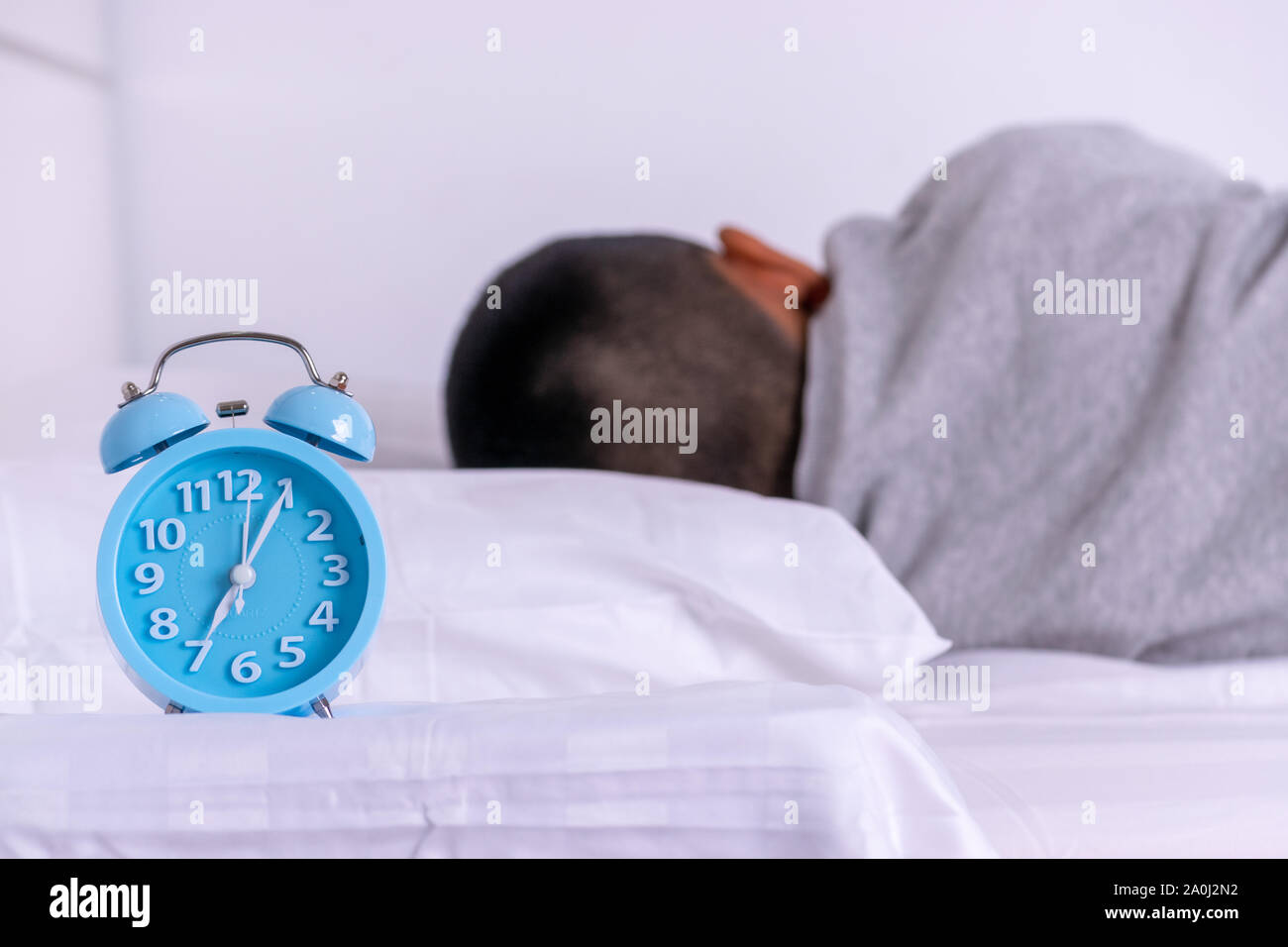 Alarm clock with boy sleeping on bed Stock Photo Alamy