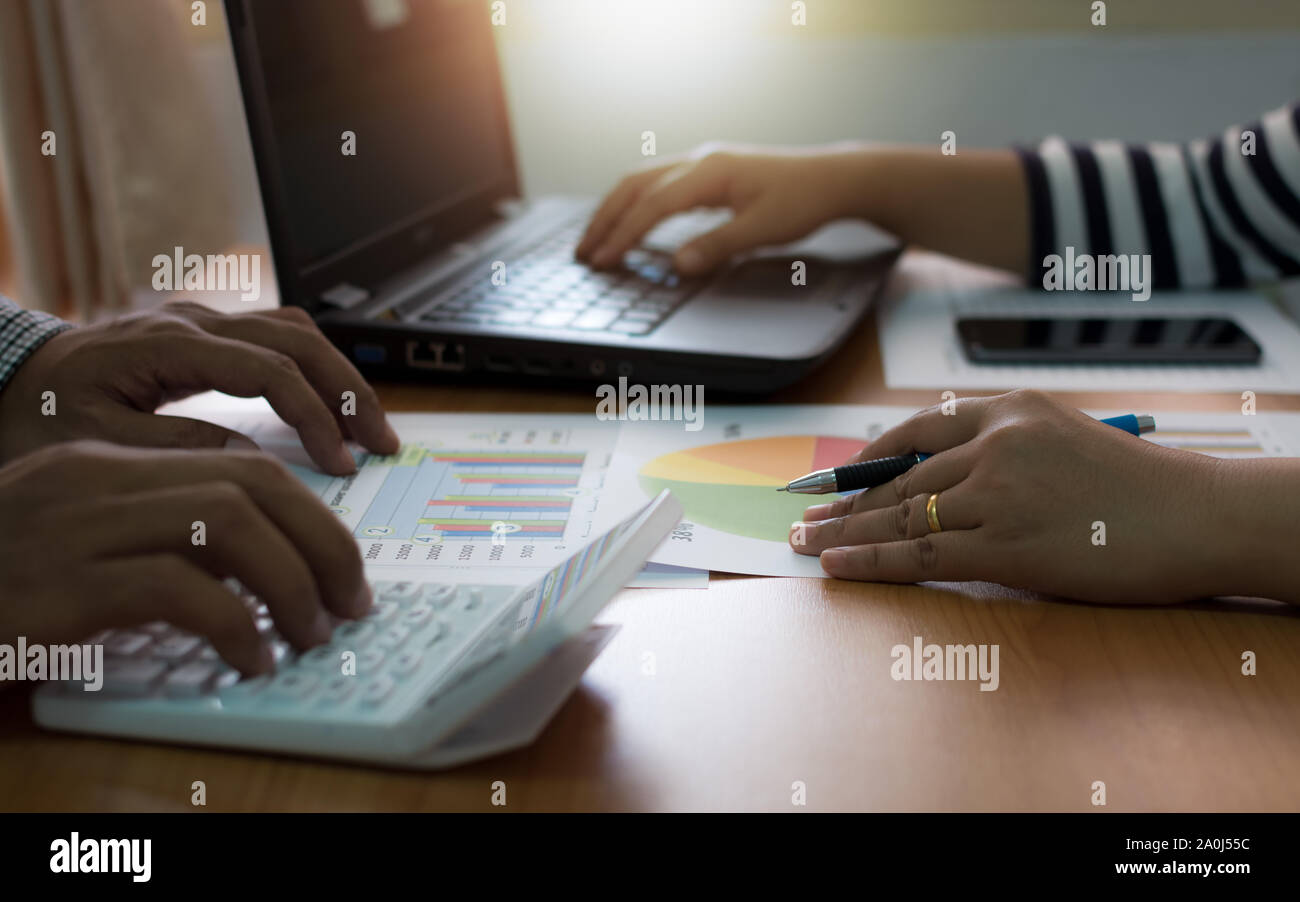 Two colleagues discussing data with laptop and calculator with