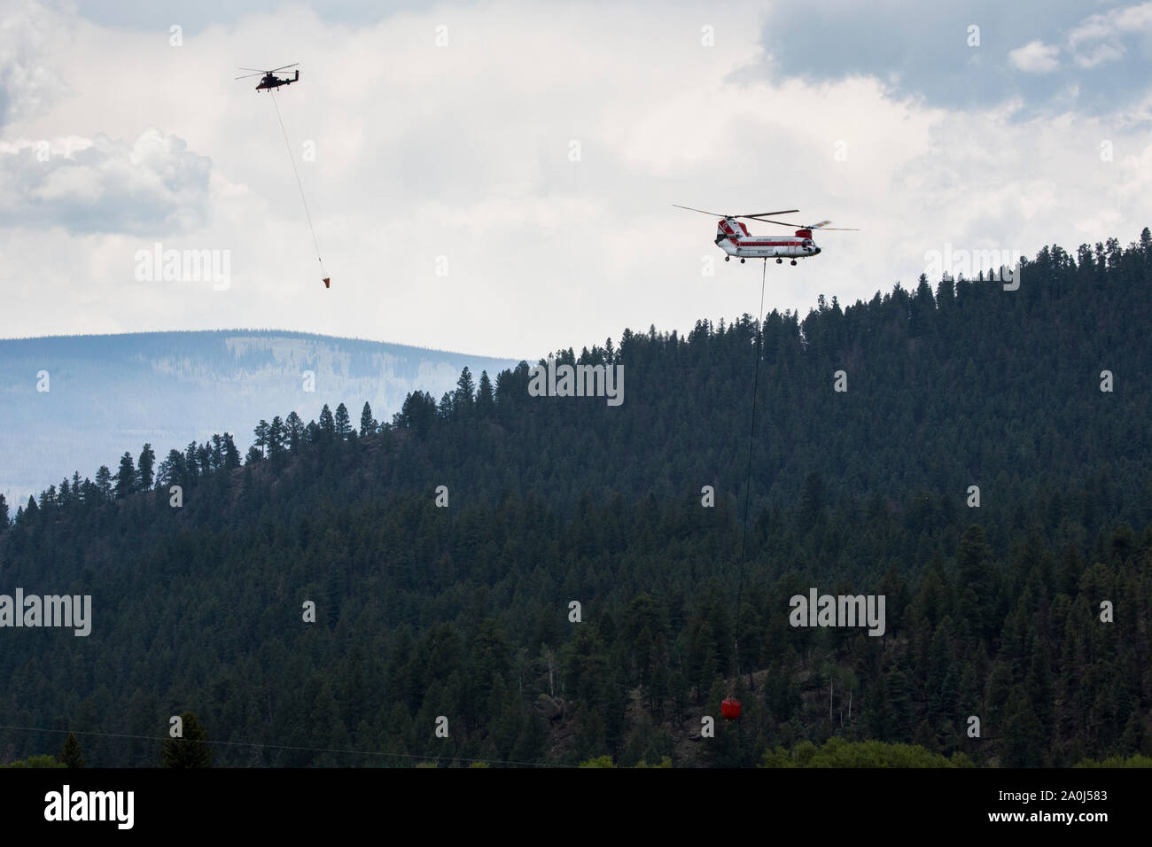 Helicopters carry water to drop on a Colorado forest fire. Stock Photo