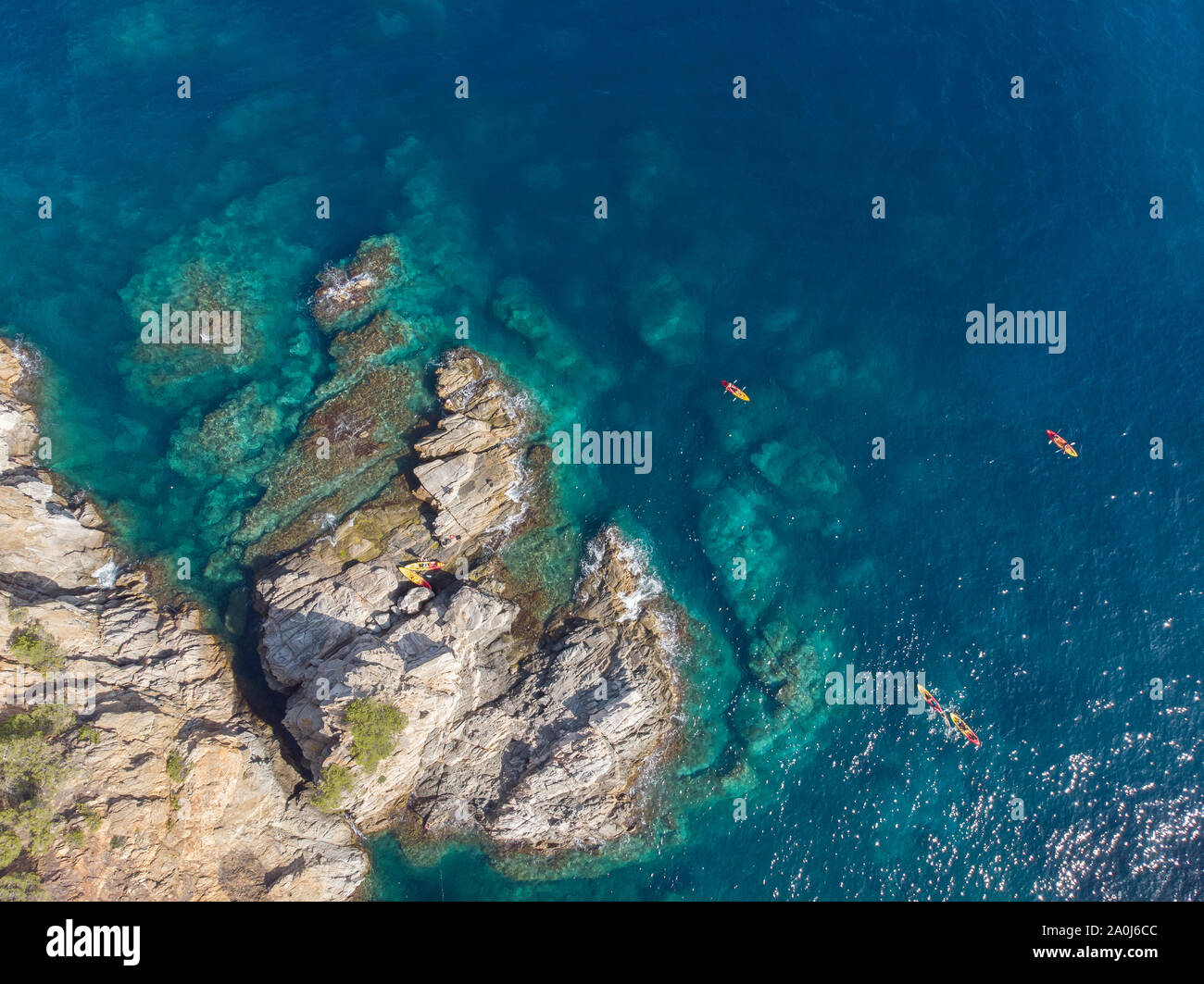 A cluster of kayaks gather off a rocky cove in the Mediterranean Stock Photo