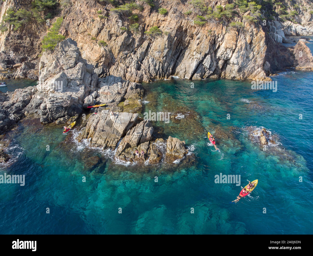 A group of friends playing and kayaking in a Mediterranean cove. Stock Photo
