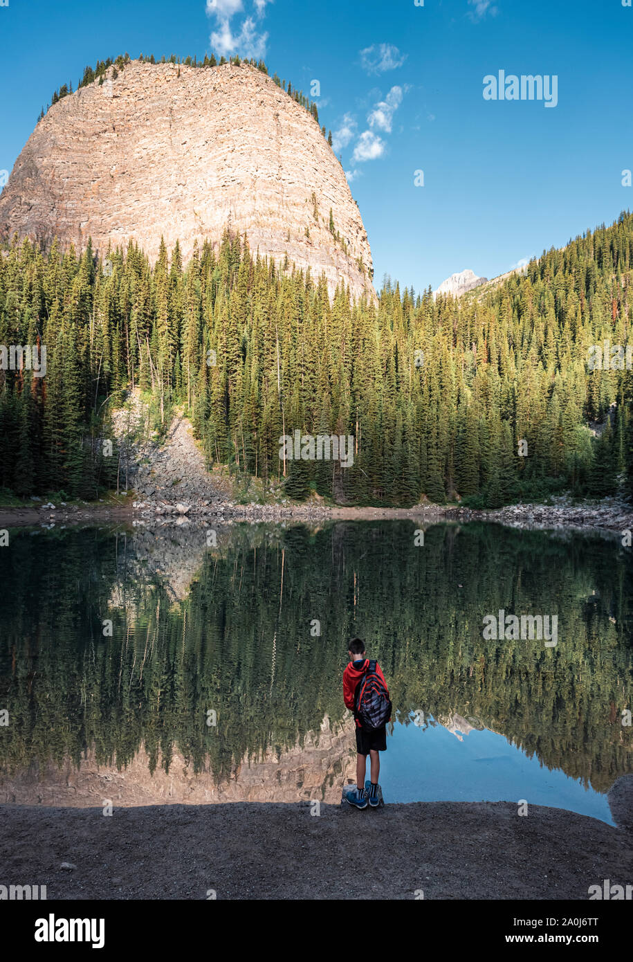 Boy standing on the edge of Mirror Lake in the Rocky mountains. Stock Photo