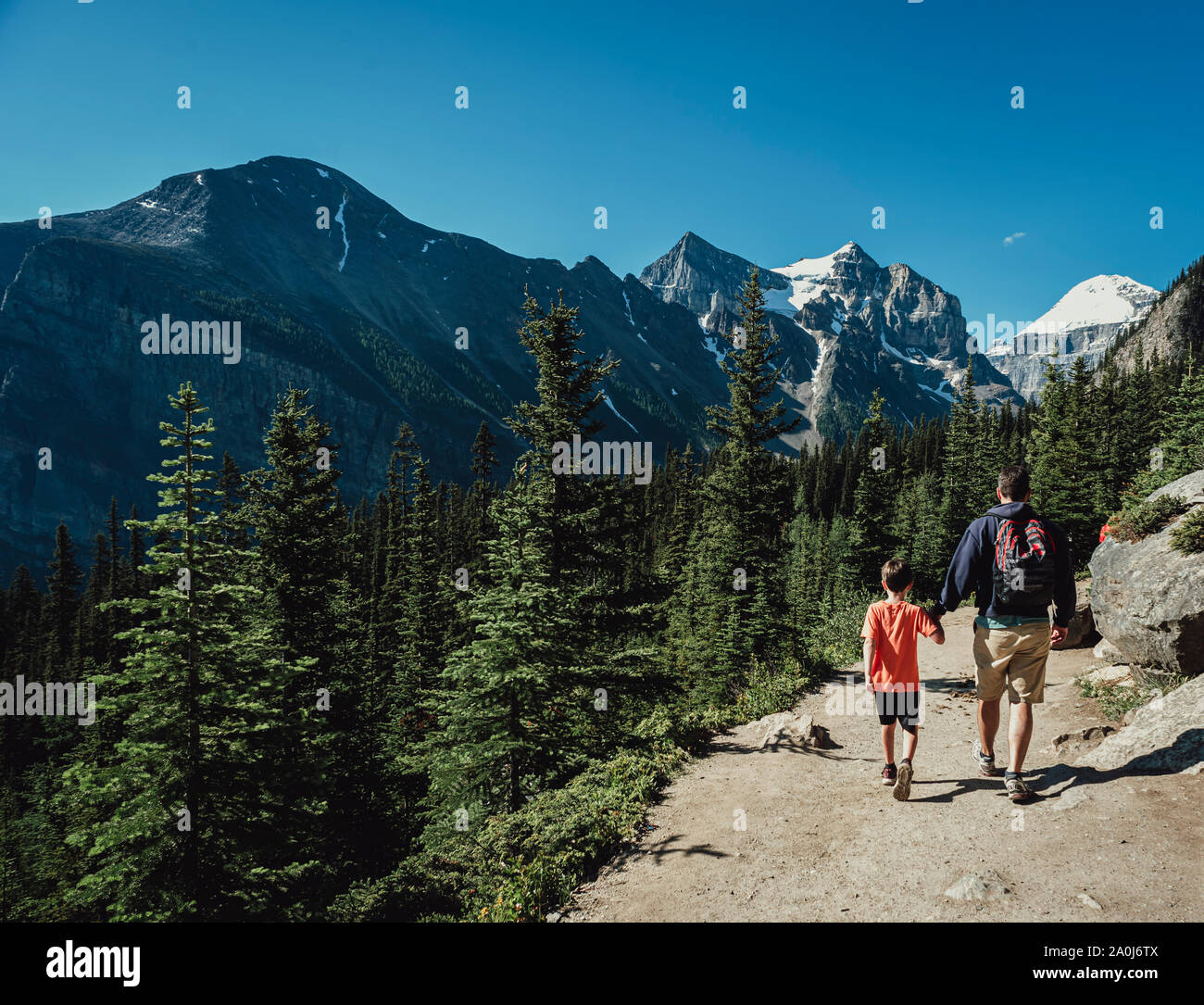 Father and son holding hands hiking on a path in the mountains. Stock Photo