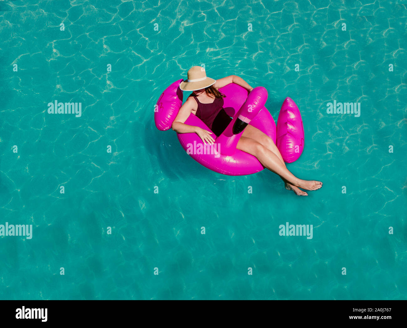 Top view of woman floating on inflatable pink flamingo in a pool. Stock Photo