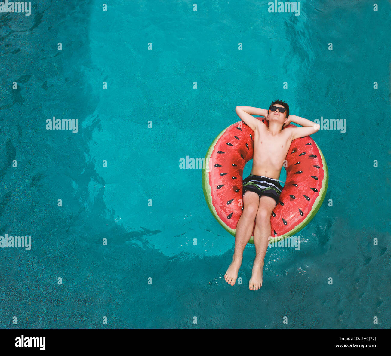 Top view of boy floating on inflatable watermelon float in a pool. Stock Photo