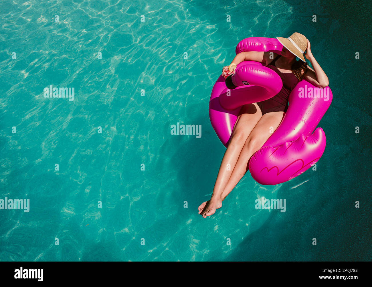 Top view of woman floating on inflatable pink flamingo in a pool. Stock Photo