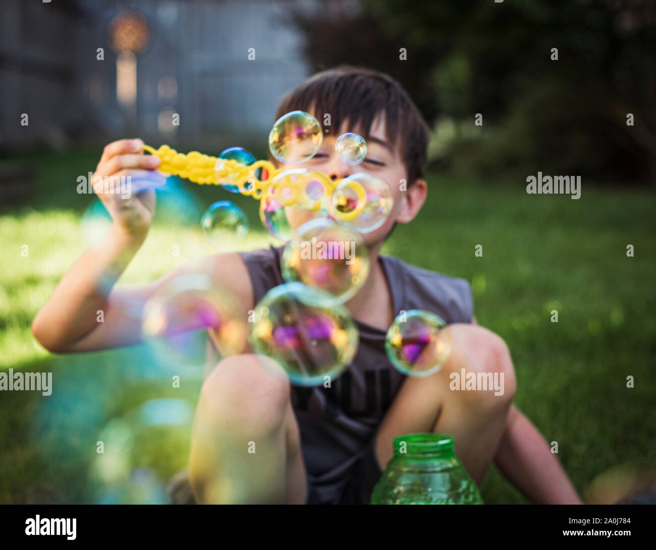 A young boy blowing bubbles outdoors on a summer day. Stock Photo