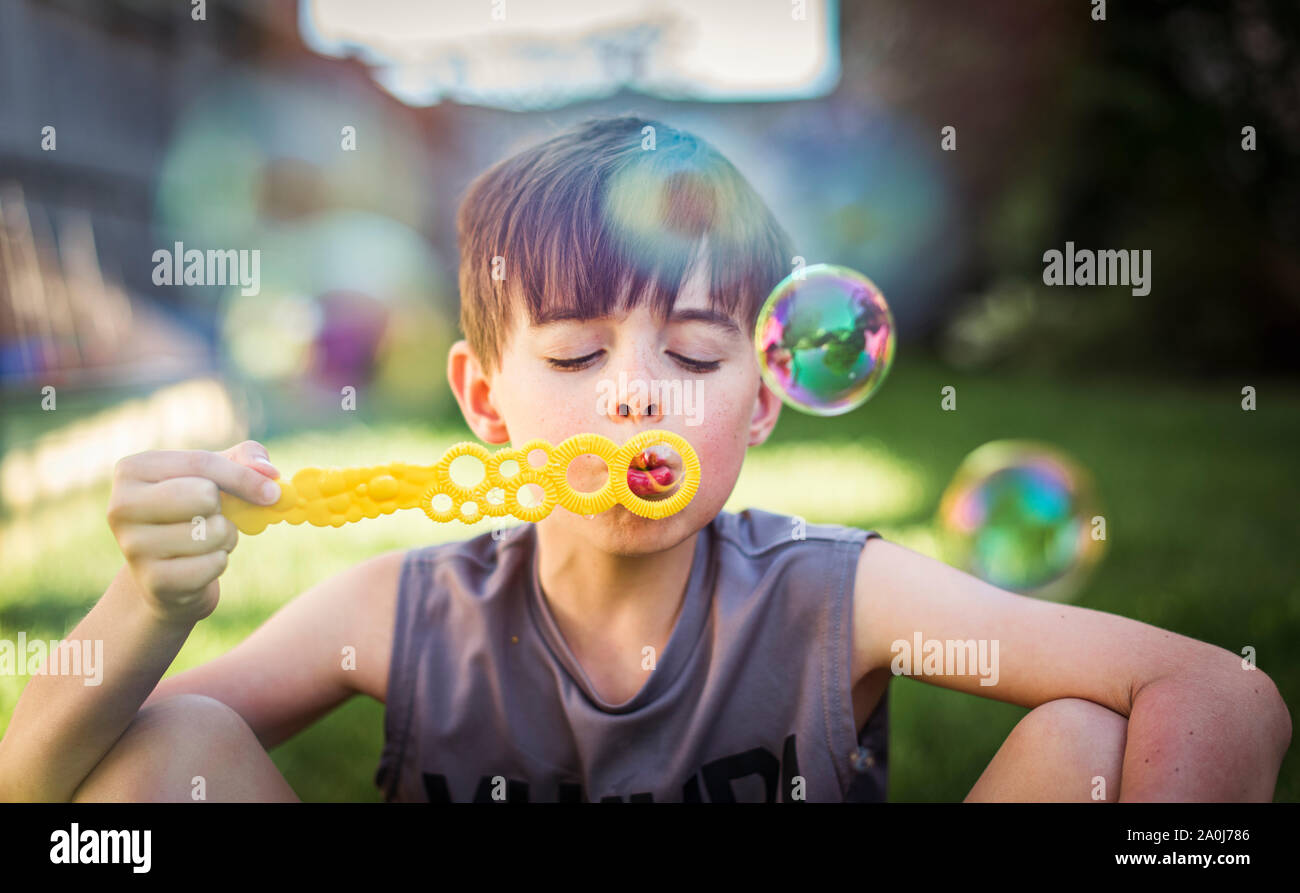 Young boy blowing bubbles outdoors on a summer day. Stock Photo