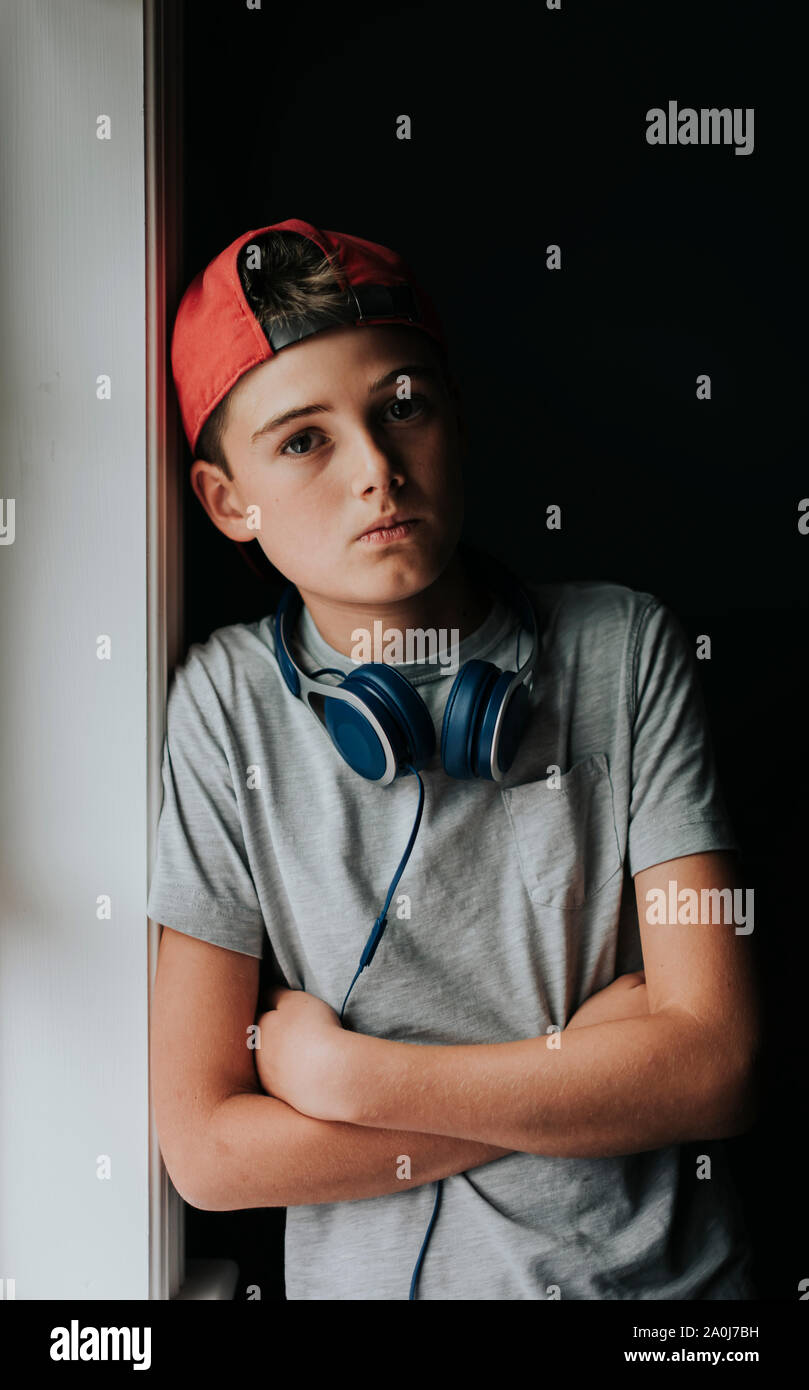 Portrait of tween boy with headphones around neck and backwards hat. Stock Photo