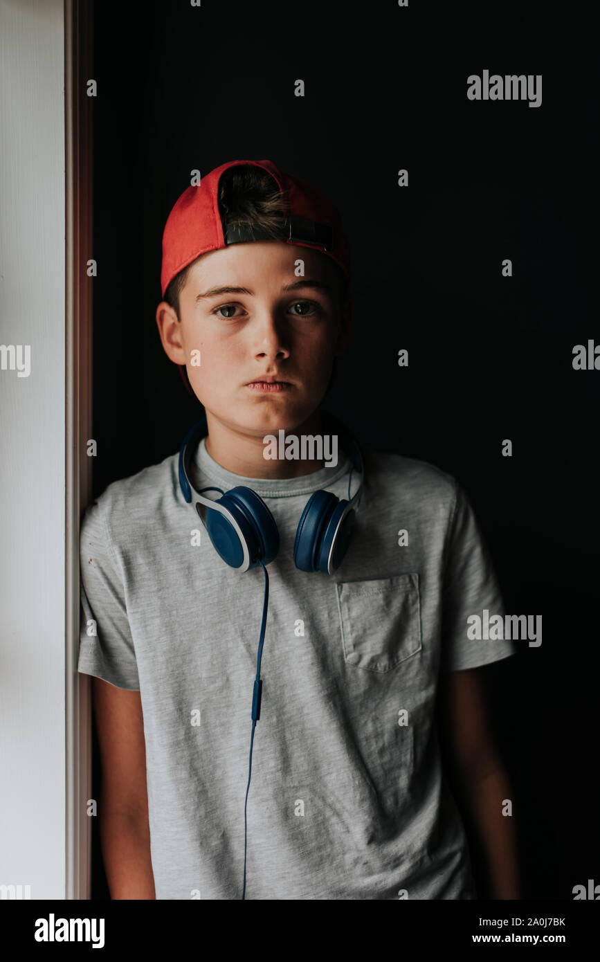 Portrait of tween boy with headphones around neck and backwards hat. Stock Photo