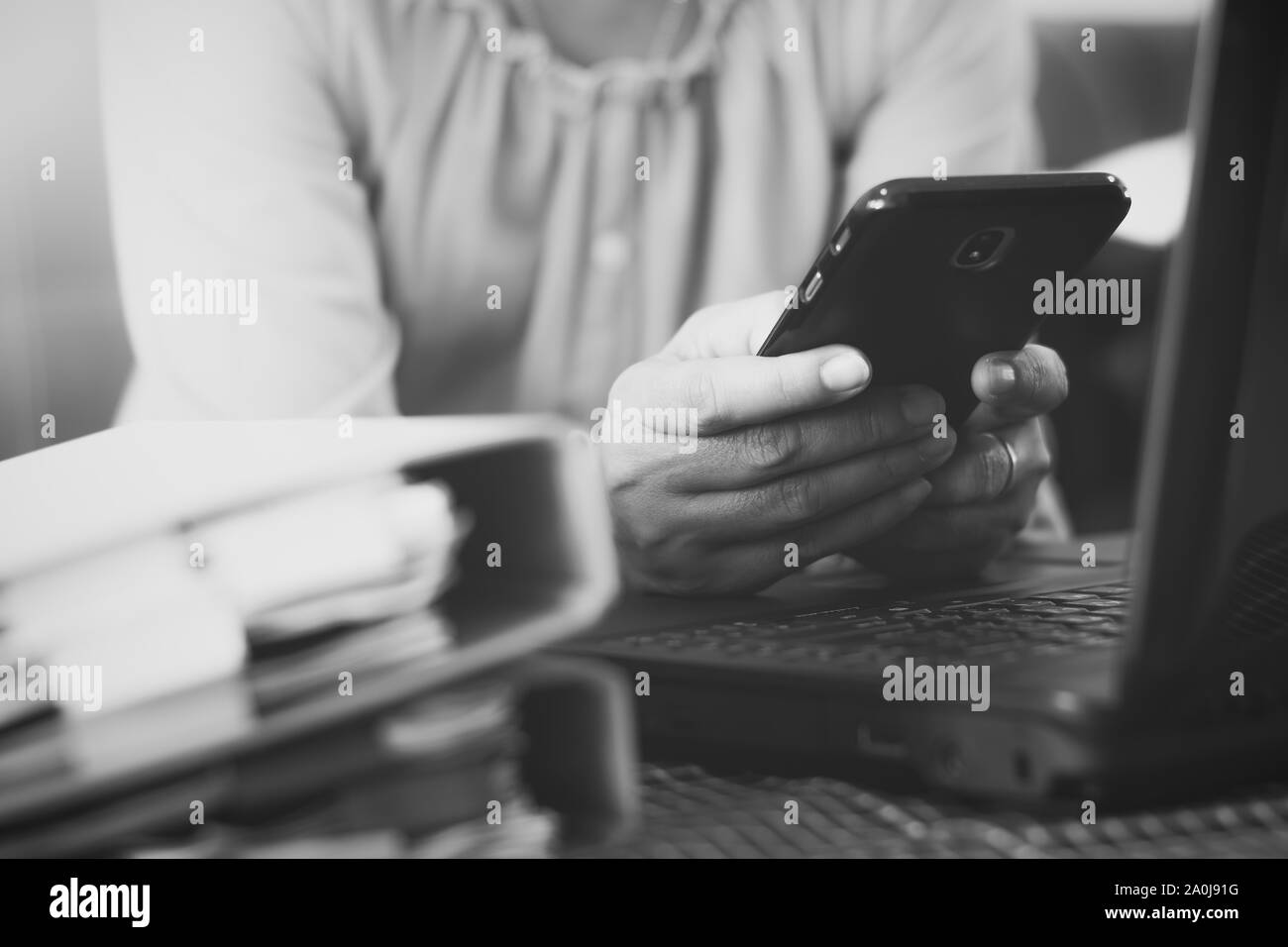 Hands of woman using mobile phone for payments online shopping with laptop and document on the table. Business and financial concept. Black and white Stock Photo