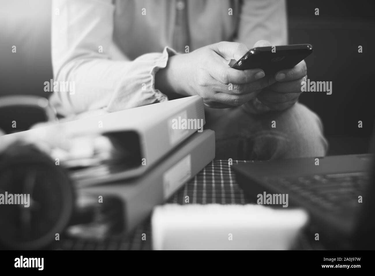 Hands of woman using mobile phone for payments online shopping with laptop and document on the table in black and white. Business and financial. Stock Photo