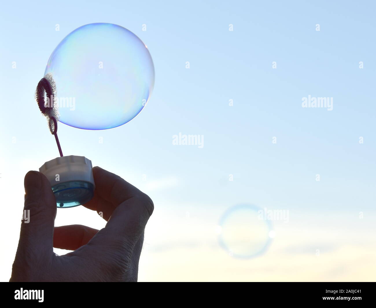 Hand holding soap bubble outdoor against sky Stock Photo