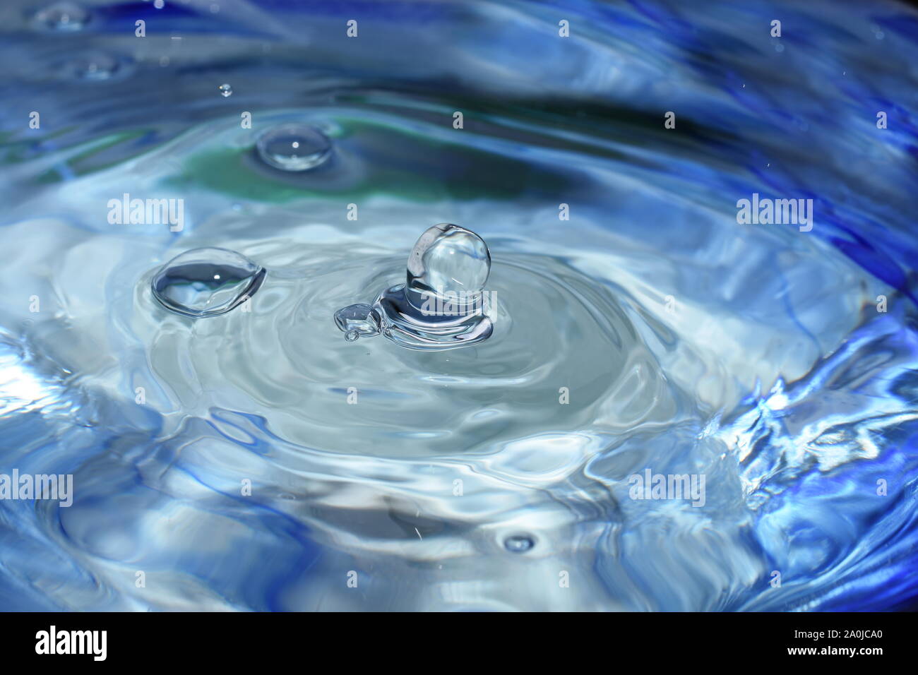 Splash and ripples in blue water liquid Stock Photo