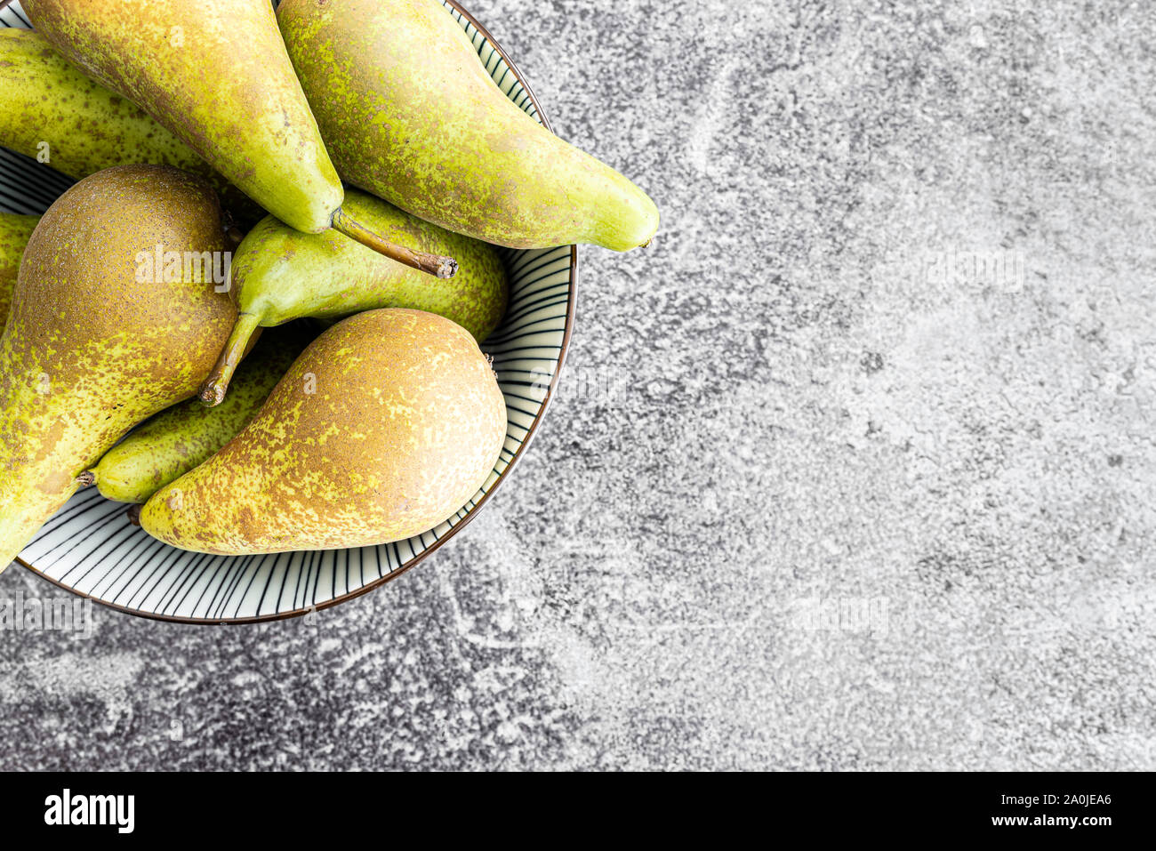 top view close-up of fresh organic pears in pottery bowl on stone kitchen counter Stock Photo