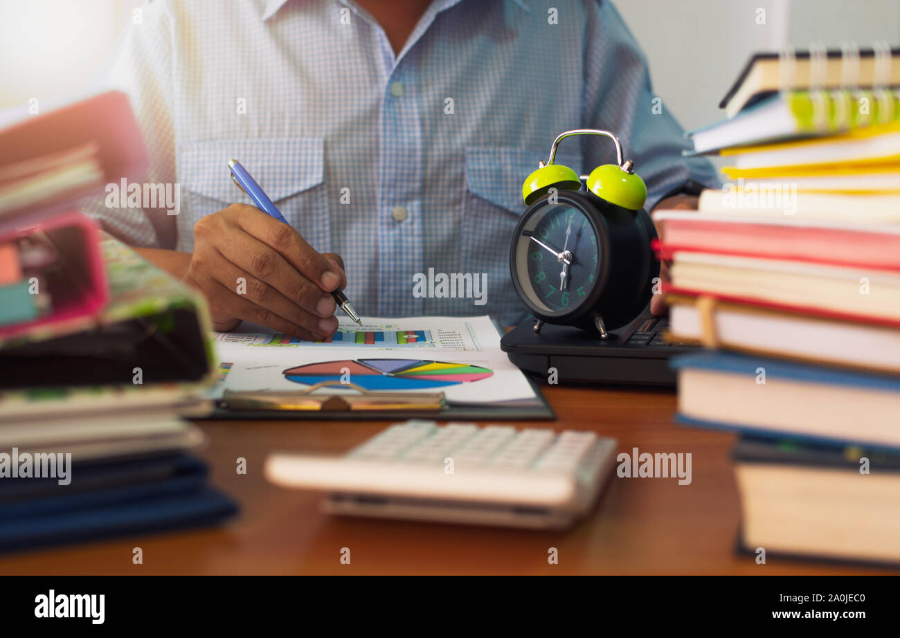 Man is working with stack of documents on office desk, Businessman is analyzing marketing with statistics chart, Business and Office life concept. Stock Photo