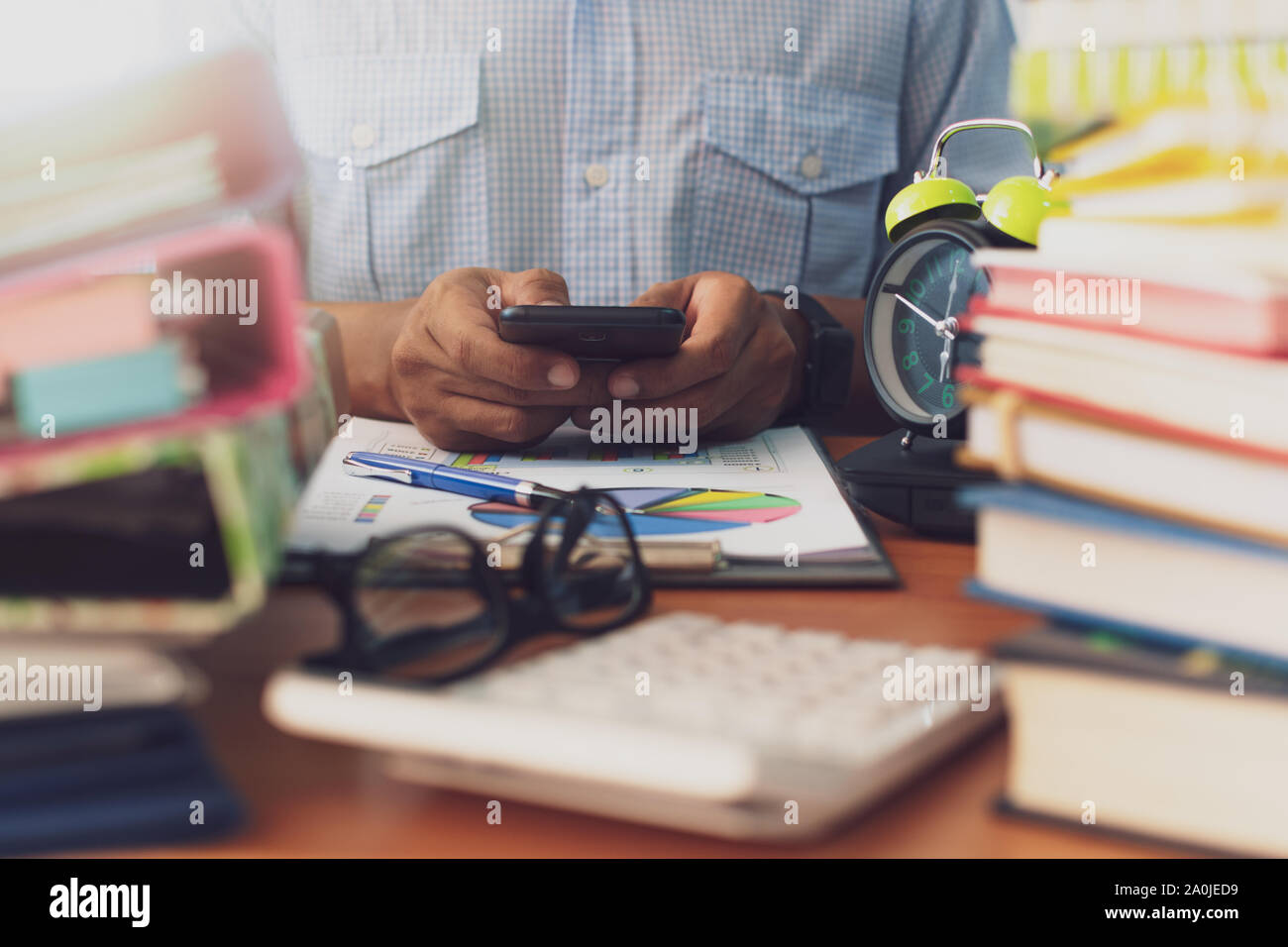 Man is using mobile phone with stack of documents on office desk, Businessman is analyzing marketing with statistics chart, Business and Office life c Stock Photo