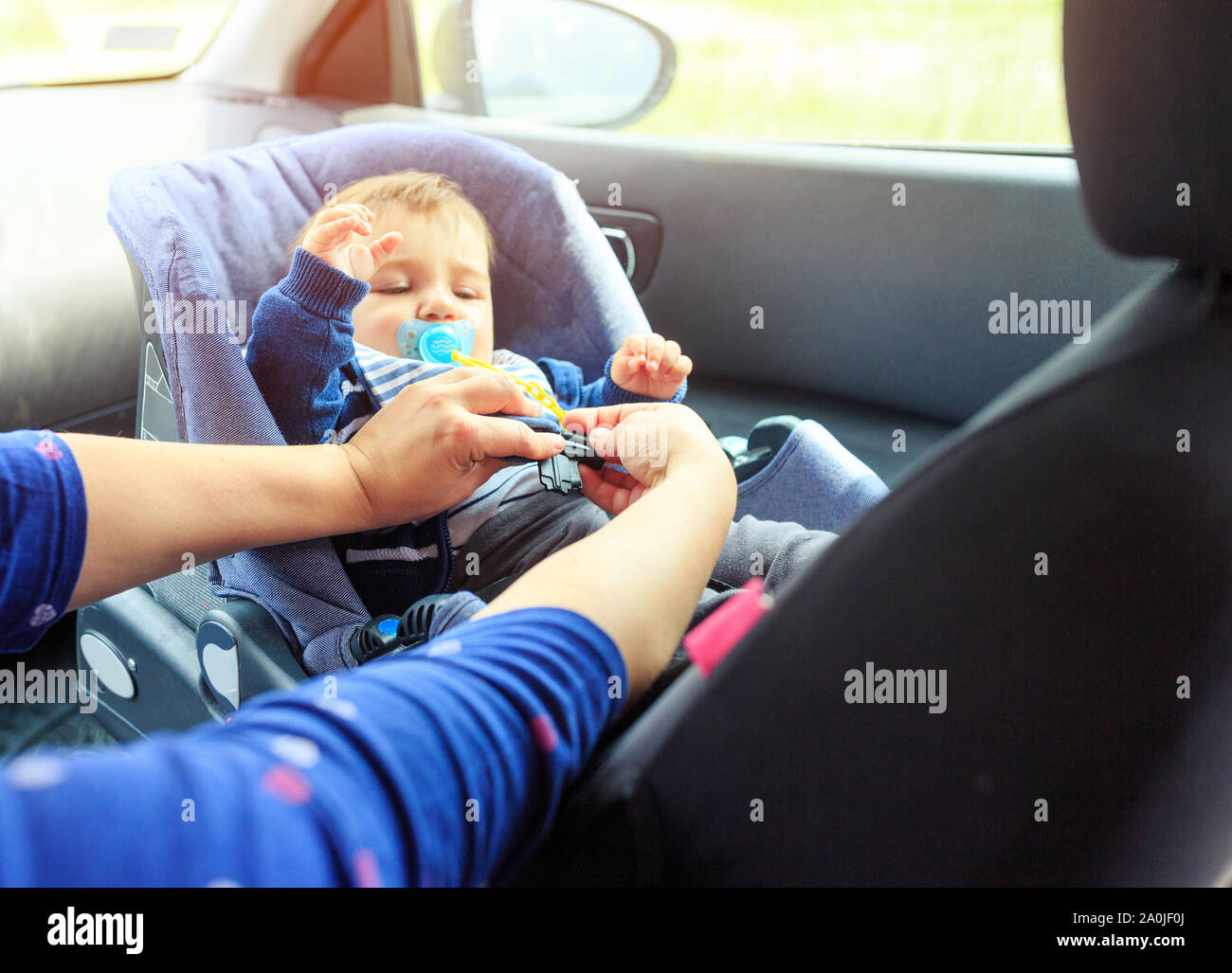 children car chair. baby car seat for safety.  Protection in the car. woman is fastening security belt to child, who is sitting in safety car seat. Ve Stock Photo