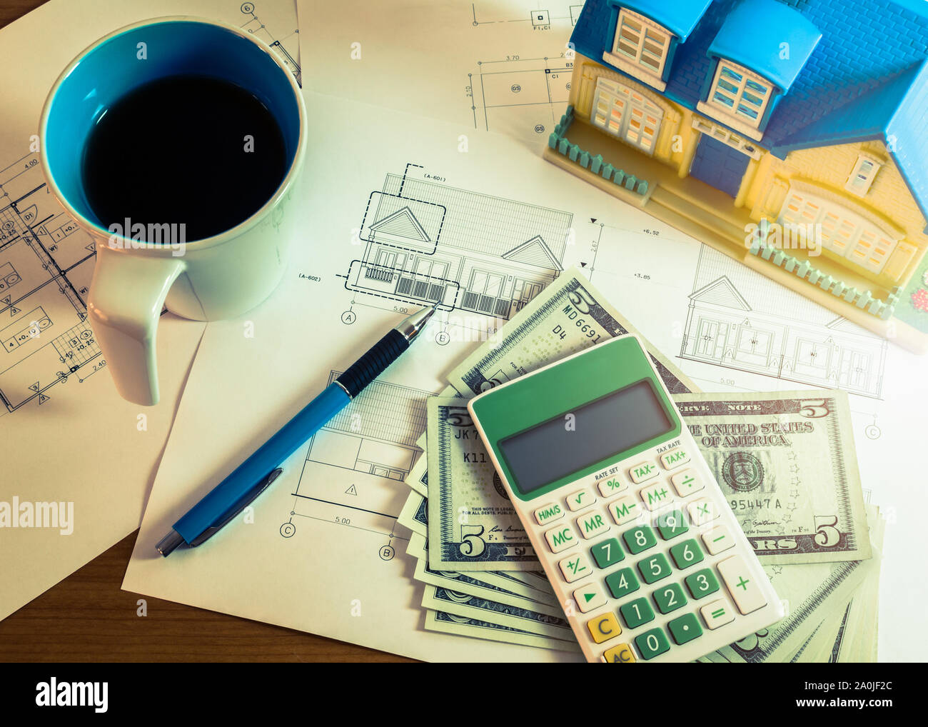 Investment for construction with limit budget, Construction plan, pen, money, model house, cup of coffee and calculator in cross processed color Stock Photo