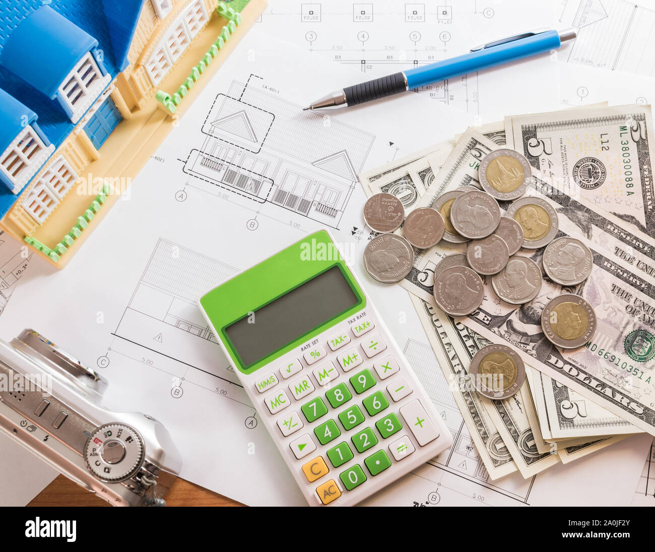 Investment for construction with limit budget, Construction plan, pen, money, model house, camera and calculator on wooden table Stock Photo