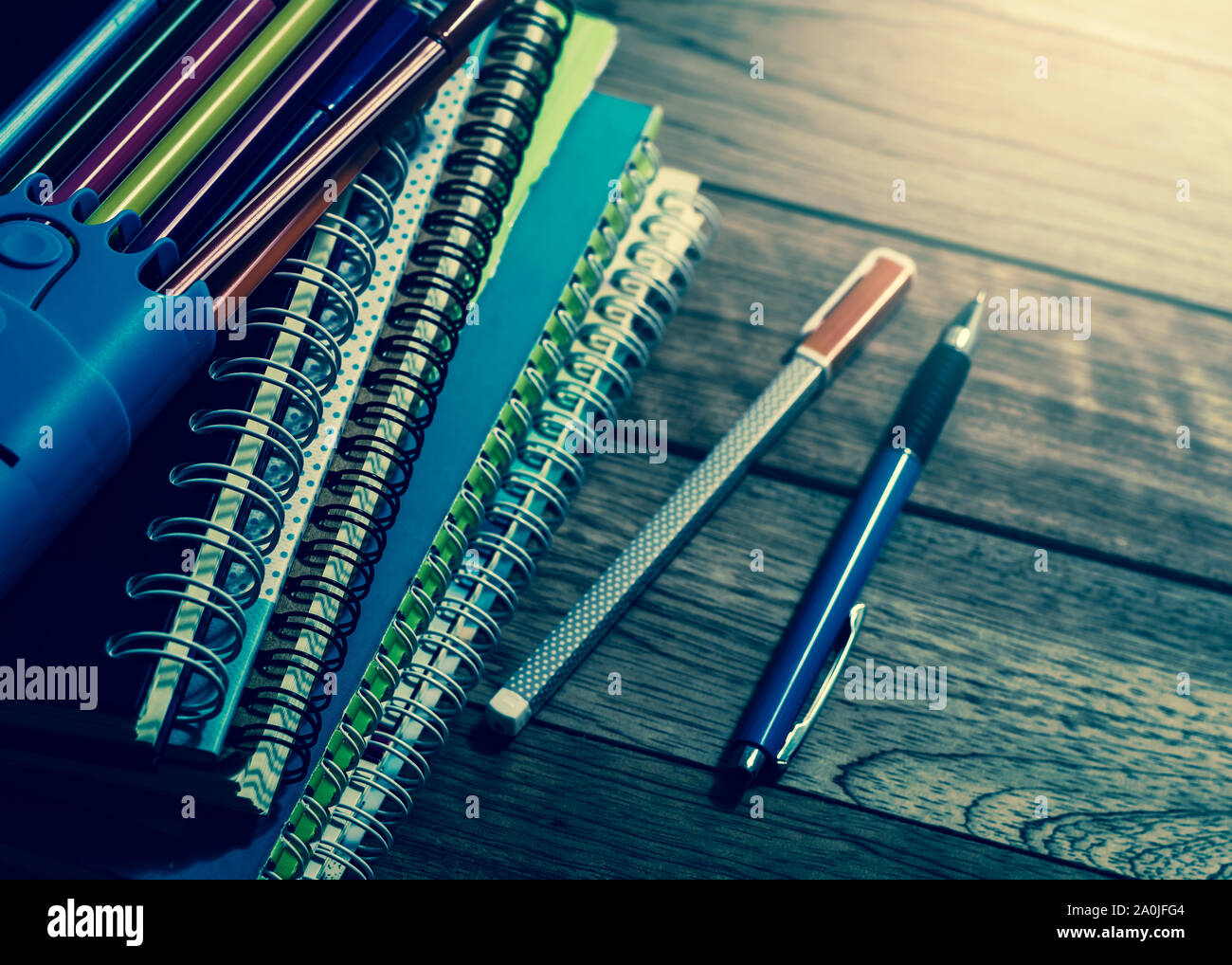 Heap of notebook with pens on wooden table under light in vintage style Stock Photo
