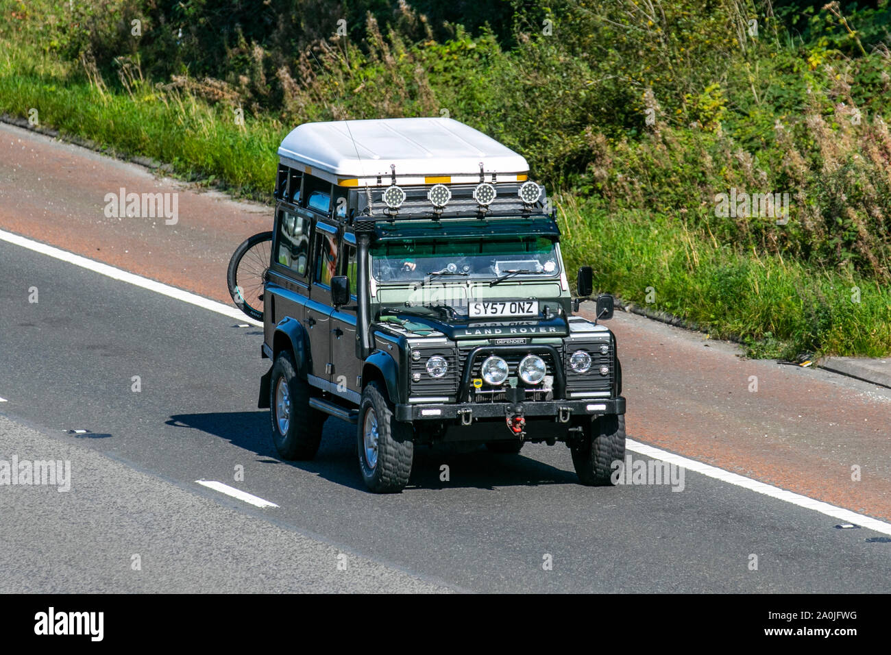2007, green Land Rover Defender, with snorkel exhaust,  UK Vehicular traffic, transport, modern, vehicles, south-bound on the 3 lane M6 motorway highway. Stock Photo