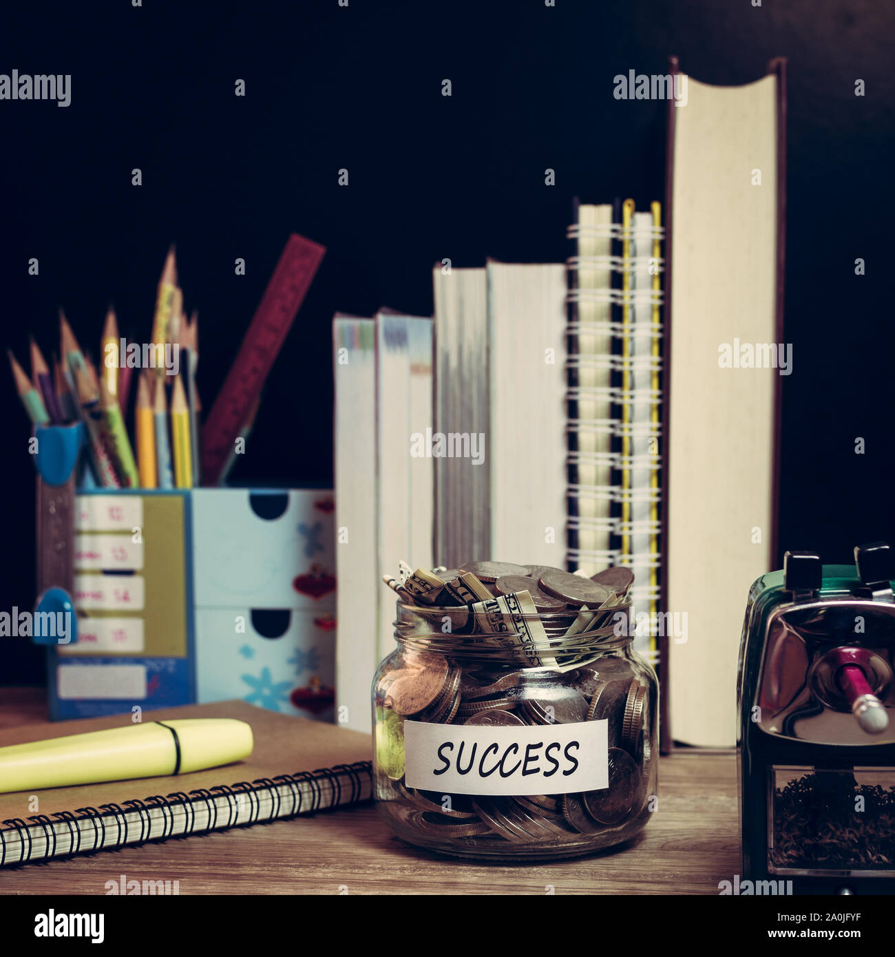 Money saving for success in the glass jar with study materials Stock Photo