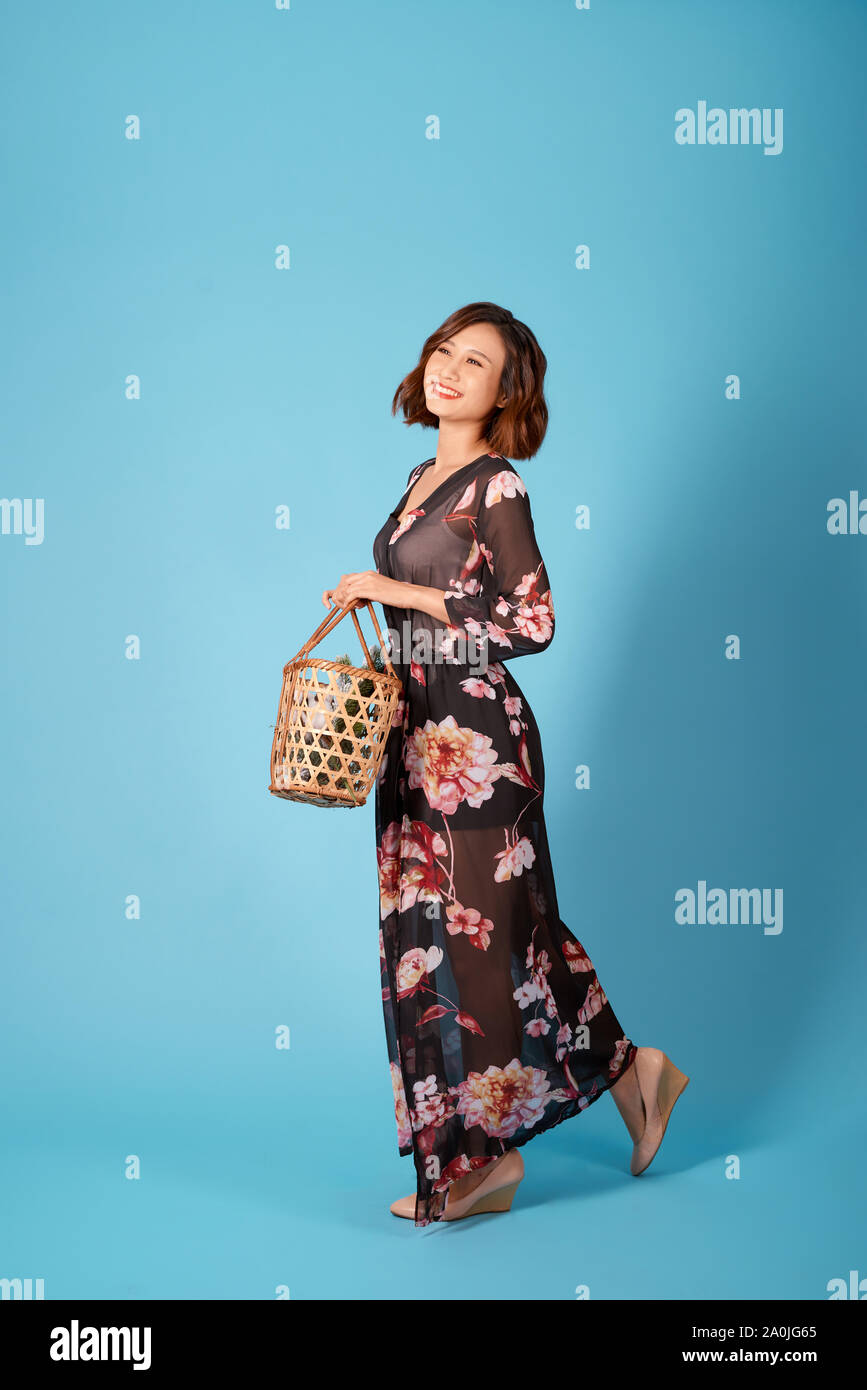 Beautiful young smiling woman in vintage dress holding a basket with ...
