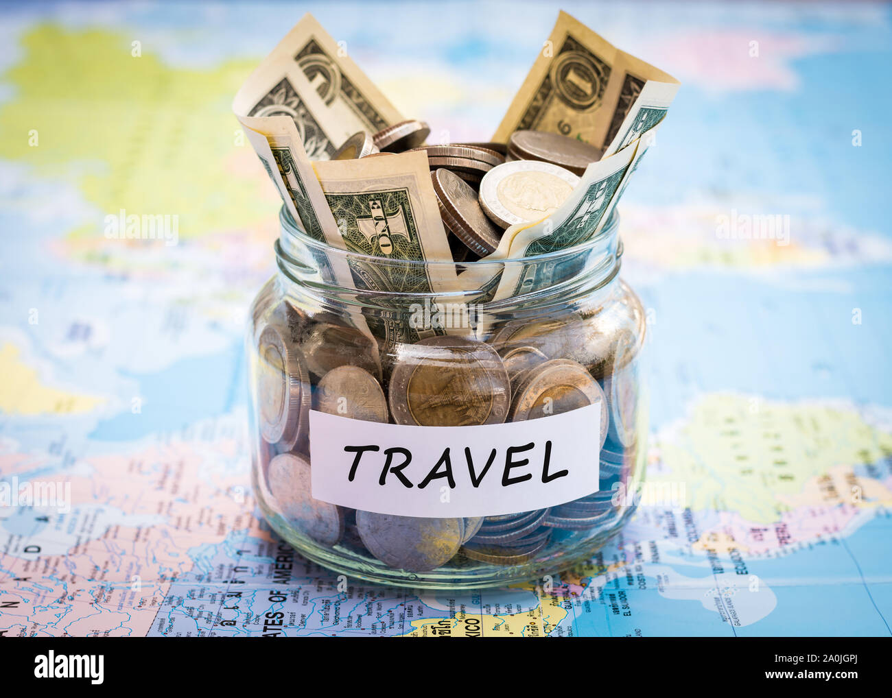 Travel budget concept. Travel money savings in a glass jar on world map Stock Photo