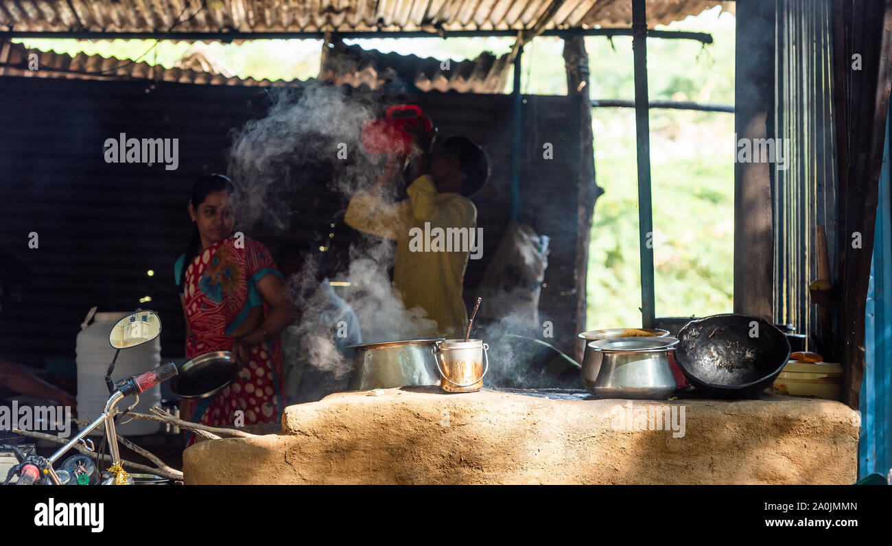 PUTTAPARTHI, INDIA - NOVEMBER 29, 2018: Indian girl cooks in the kitchen. With selective focus Stock Photo