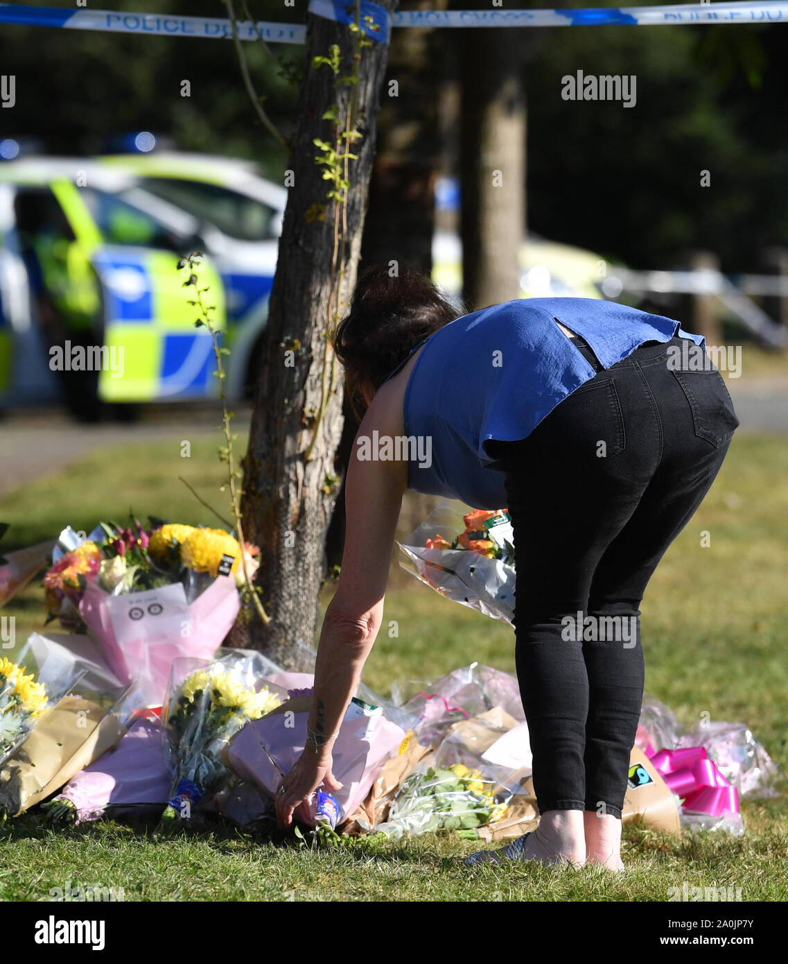 A woman places a floral tribute in Edgar Close, next to Wigginton Park, Tamworth, Stafffordshire after a 20-year-old woman died there on Thursday evening. Stock Photo
