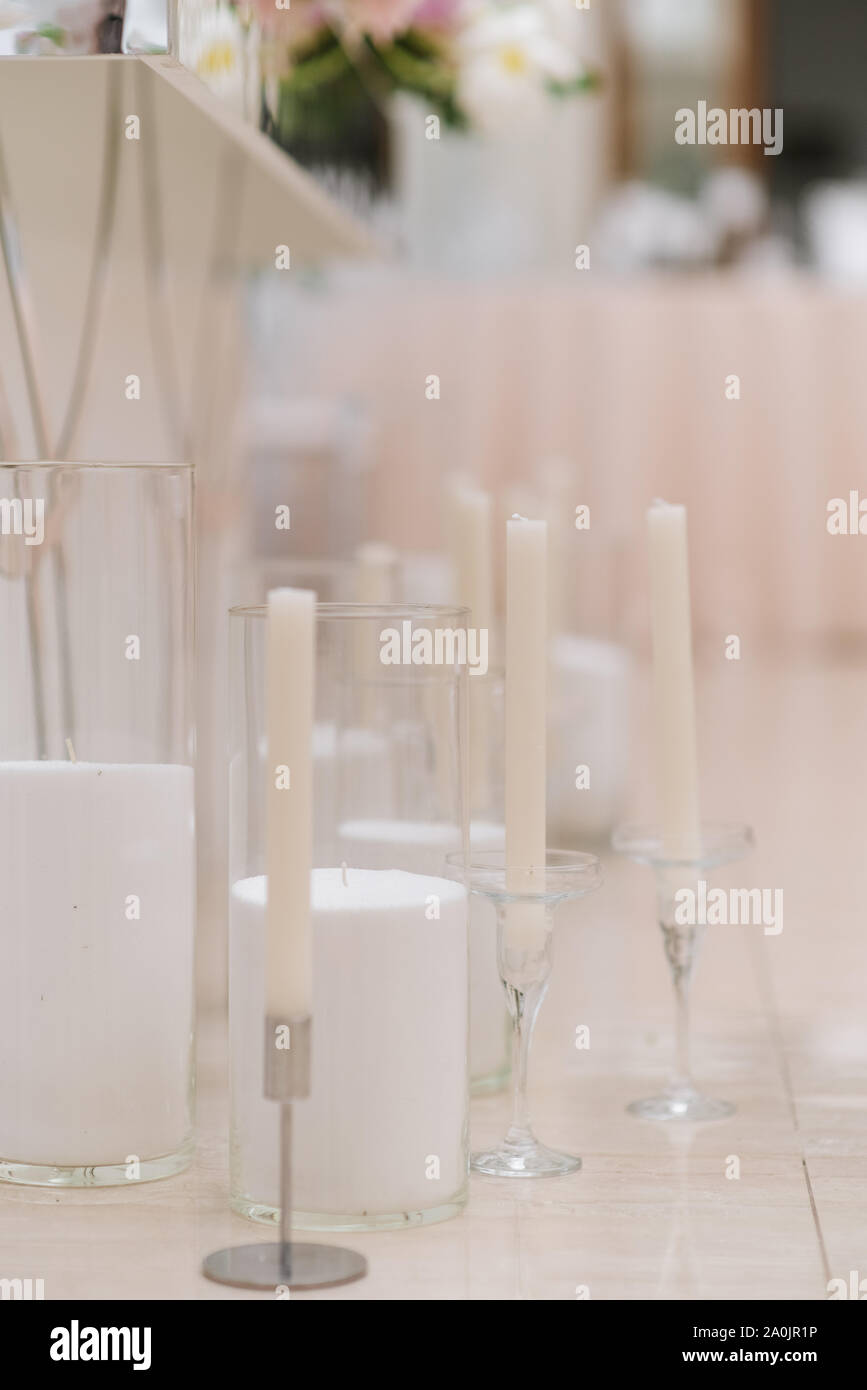 Stylish white candles in elegant glass candlesticks on a white background Stock Photo