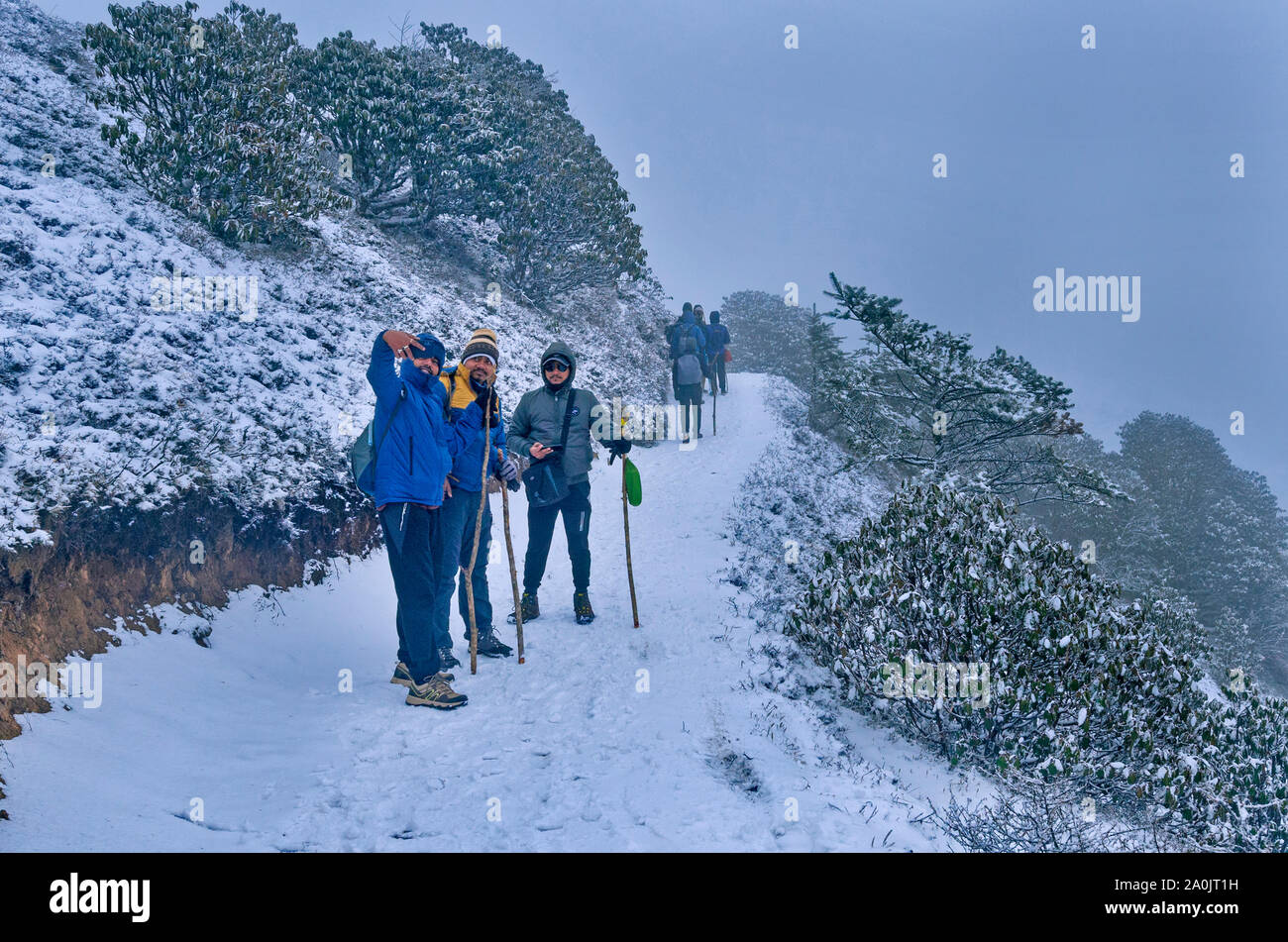 Hikers are taking selfie while walking through a snowy mountain trail. Stock Photo