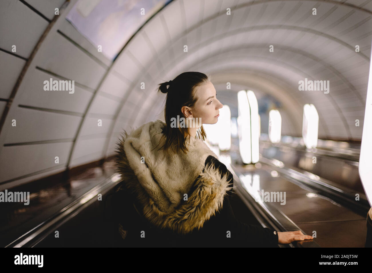 Young woman standing on escalator at subway station Stock Photo