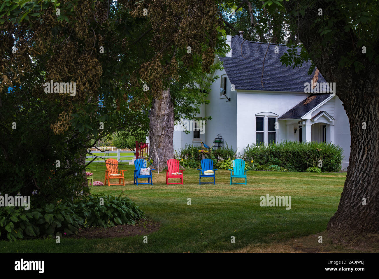 Brightly colored garden chairs add contrast and interest to a rural home and yard. Stock Photo