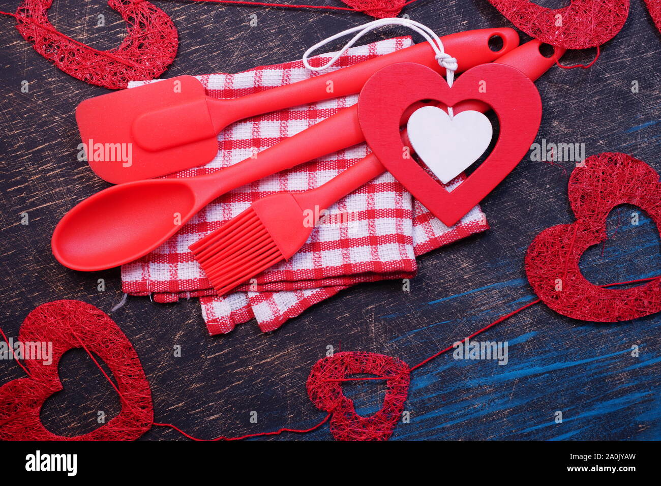 Red plastic kitchen utensils on a black table with checkered towels Stock Photo