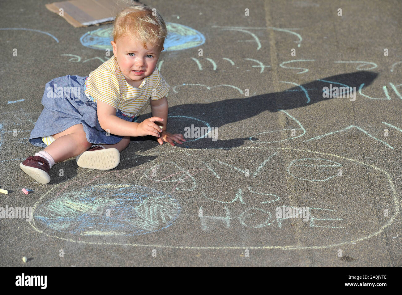 Glasgow, UK. 20 September 2019.  PICTURED: An infant stands above a globe with a slogan which reads 'GIVE US HOPE'. Will there be anything left for our future generations? Scenes from a planned protest in George Square this afternoon after strikes started a year ago by 16-year-old Swedish schoolgirl named Greta Thunberg. Hundreds of chalk marked slogans littered the concrete of George Square with protestors from all ages and backgrounds. Credit: Colin Fisher/Alamy Live News Stock Photo