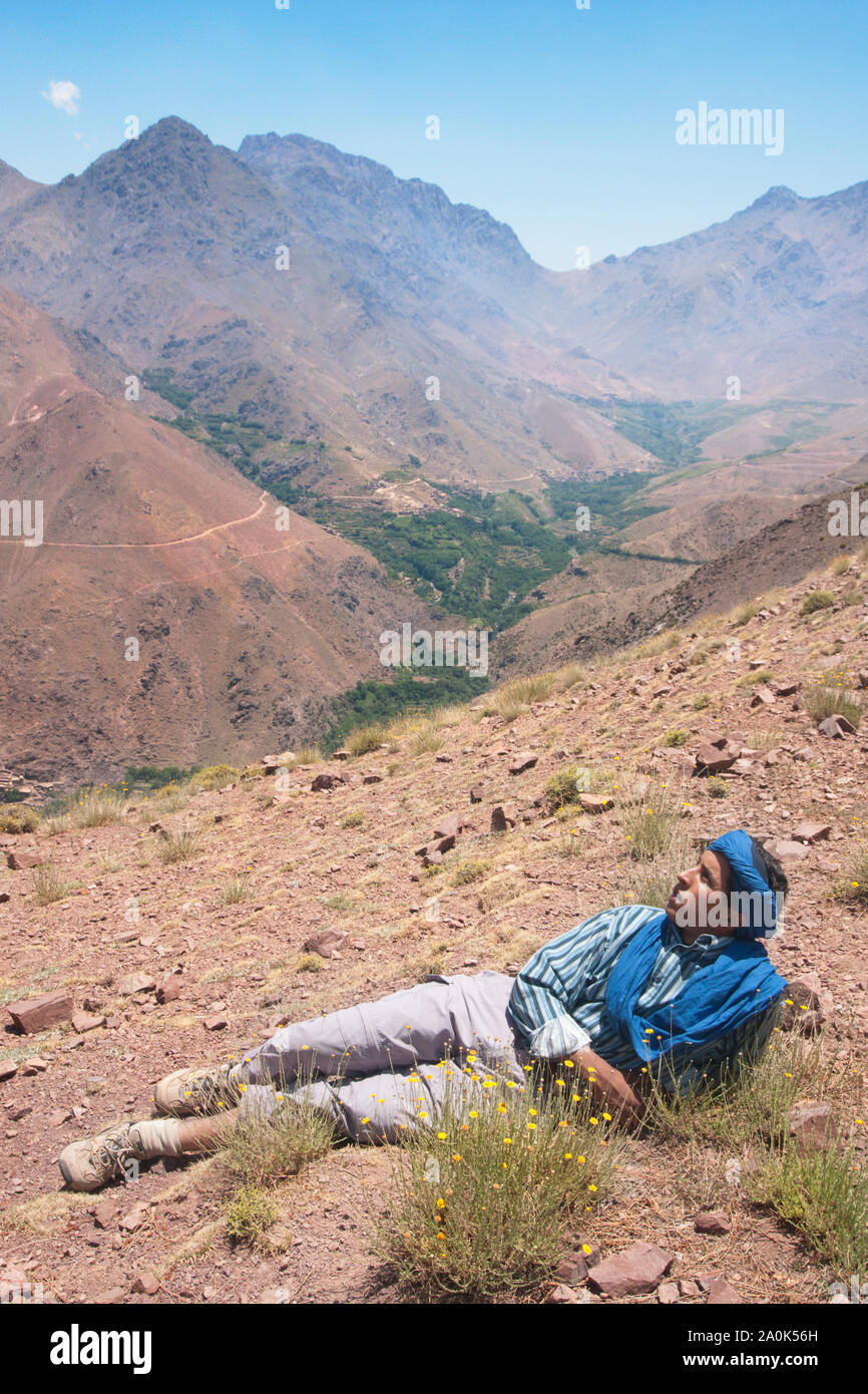 Moroccan man in his 20's pauses to rest  at Tizi 'n Tamer, 2200 meters high in Ait Mizane valley, High Atlas Mountains, Morocco Stock Photo