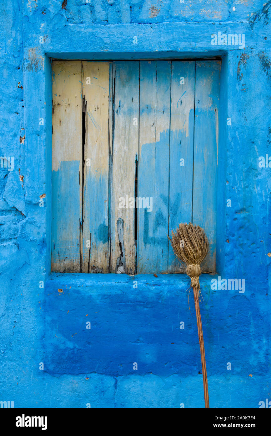 Straw broom leaning on on blue house window Stock Photo