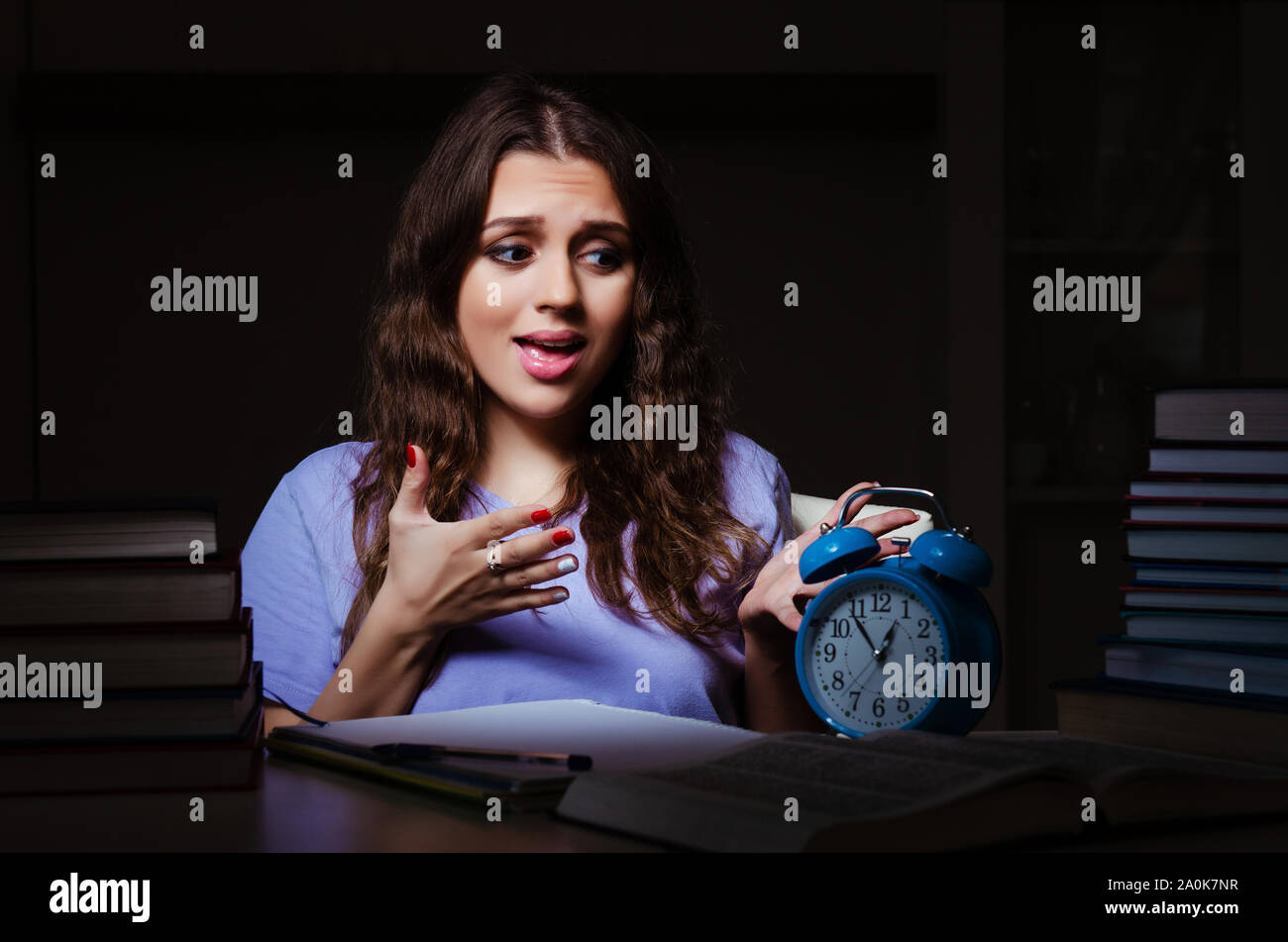 The young female student preparing for exams late at home Stock Photo ...
