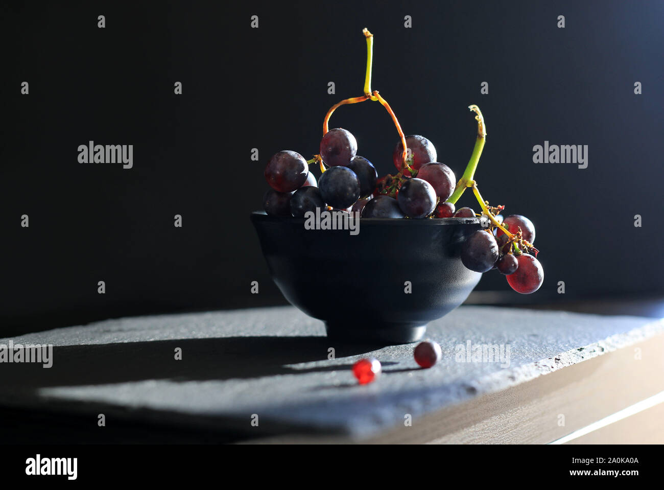 Fresh black grapes in a black cup isolated on dark background Stock Photo