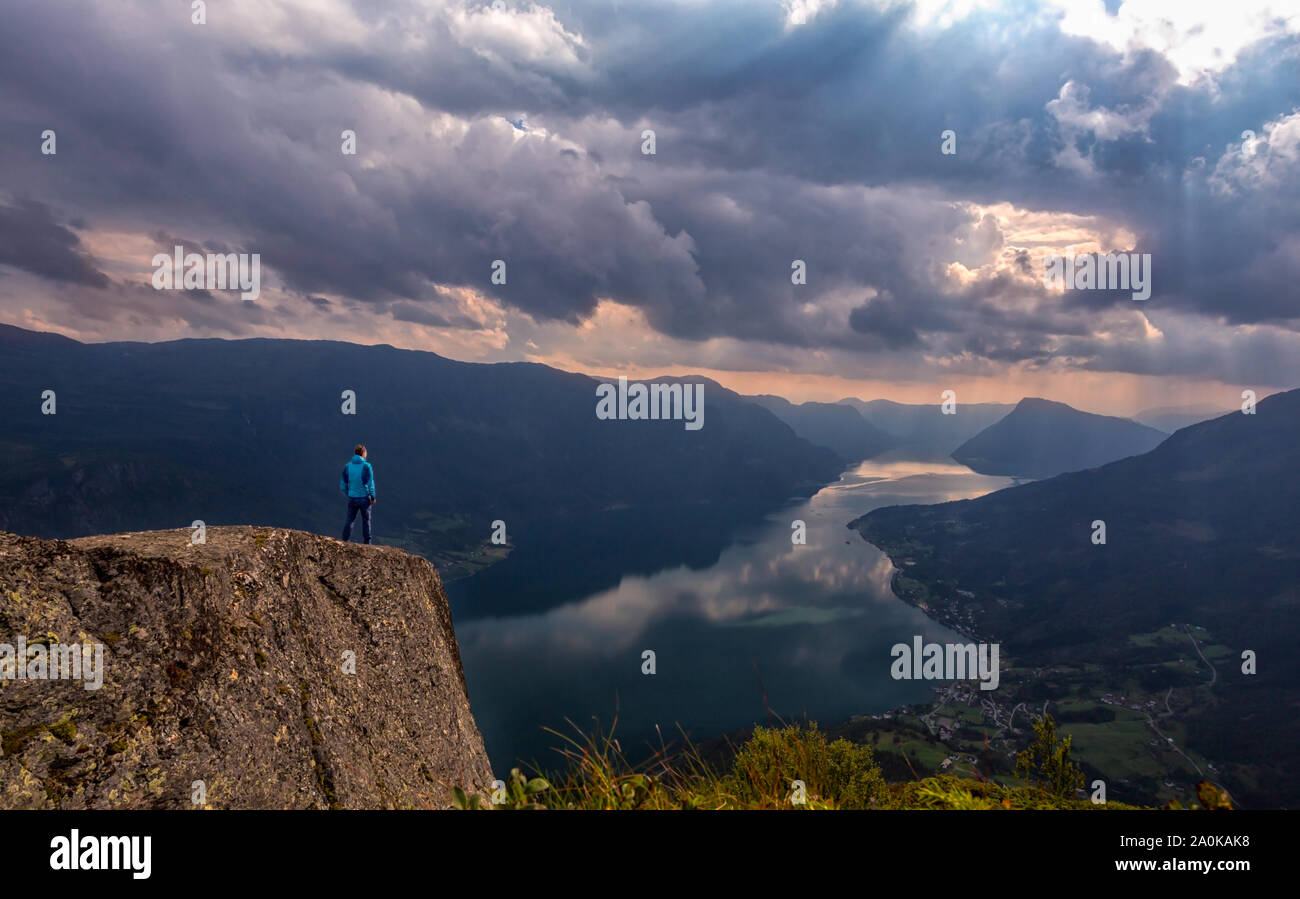 Hiker on boersteinen lookout with dramatic sky over lustrafjord Stock Photo