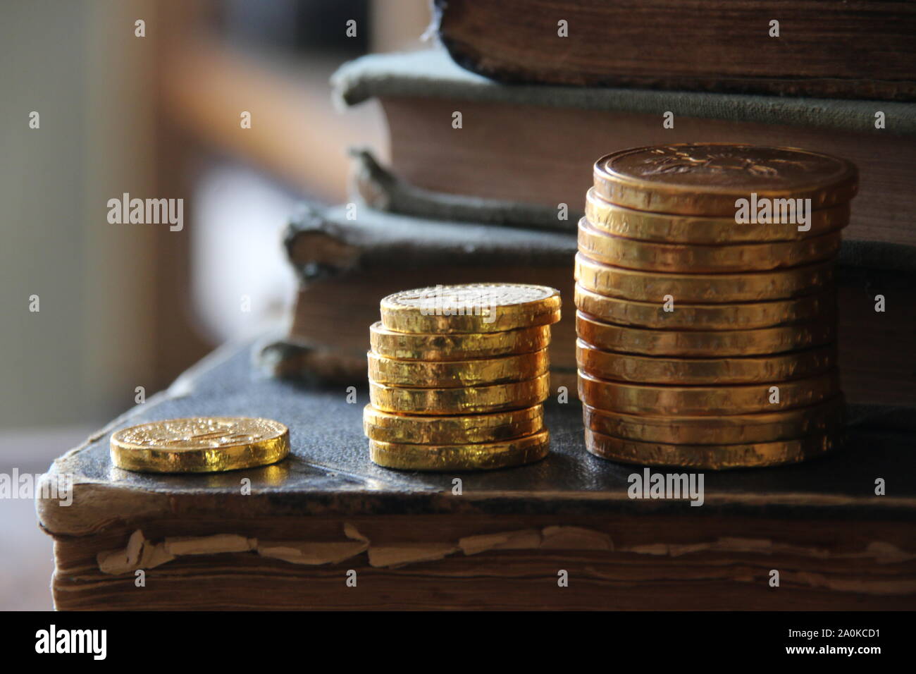 Money growth idea. Stacks of gold coins and vintage books. Stock Photo