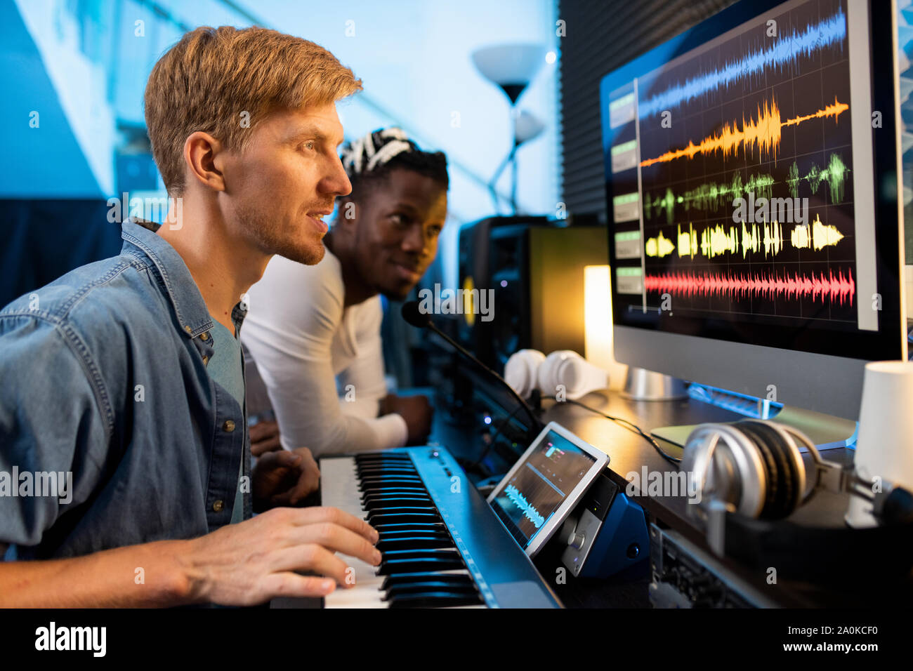 Young man with pianoboard looking at computer screen during work in studio Stock Photo