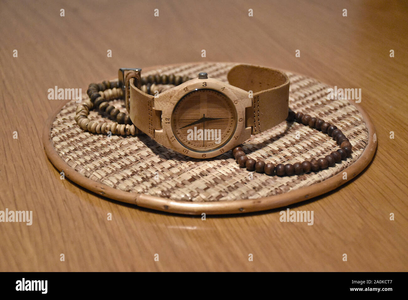 Eco-friendly, plastic-free and hand-made bamboo watch with leather strap from Thailand on a braided hemp plate surrounded by wooden bracelets on a woo Stock Photo